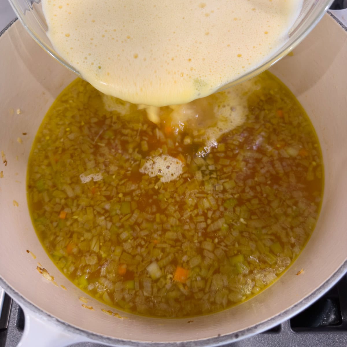 Pouring egg-broth-lemon juice mixture into the sop base.