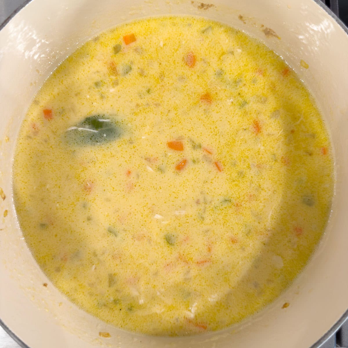 A golden creamy soup being cooked for Greek avgolemono soup.