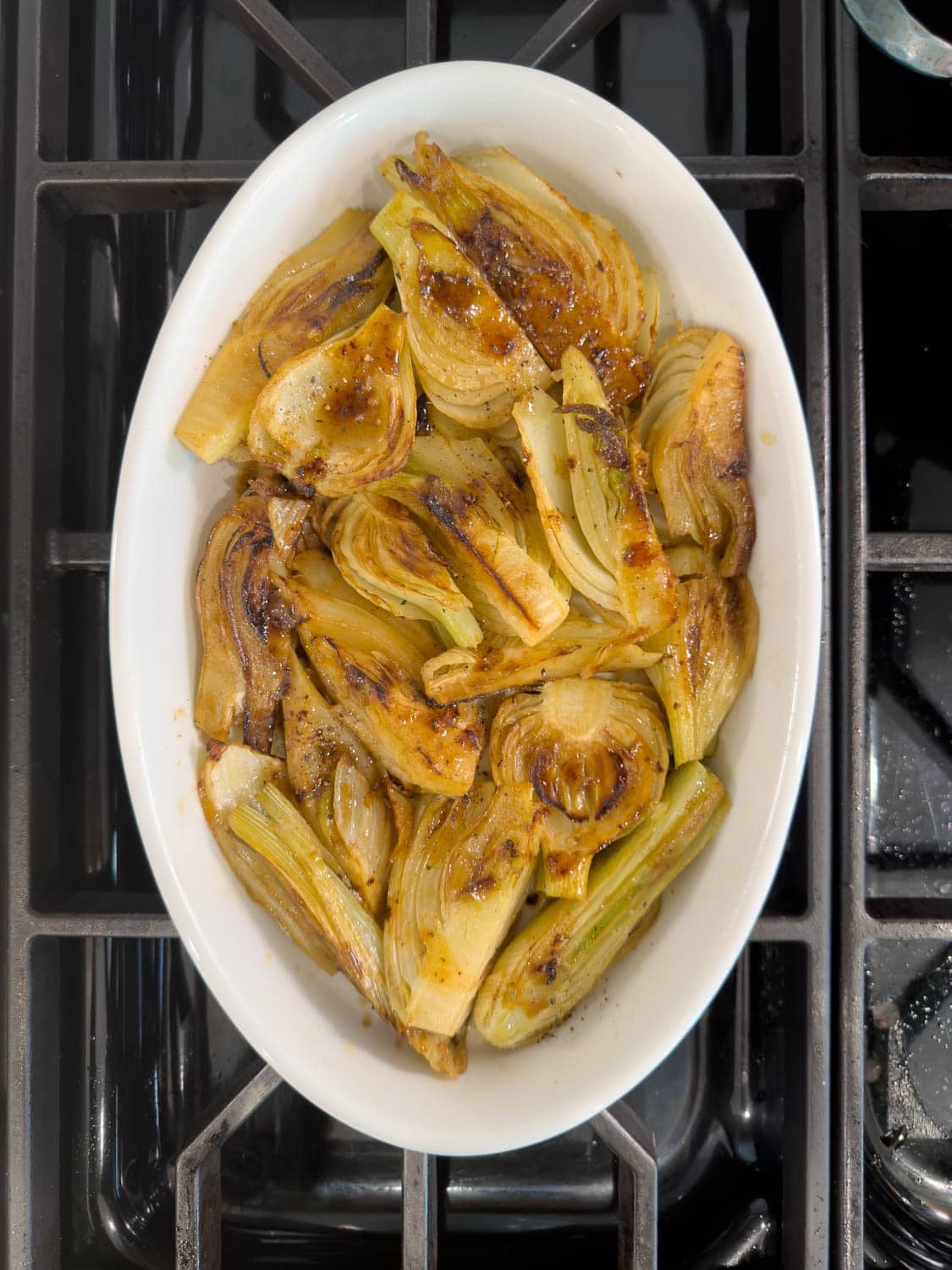 An oval casserole with golden, braised fennel wedges.