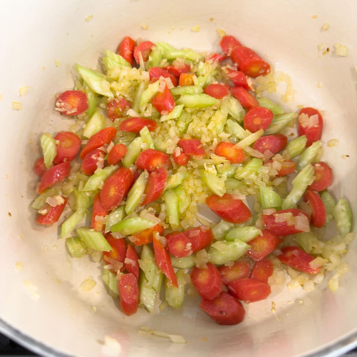 Red carrots in a pot with onions and celery for making soup.
