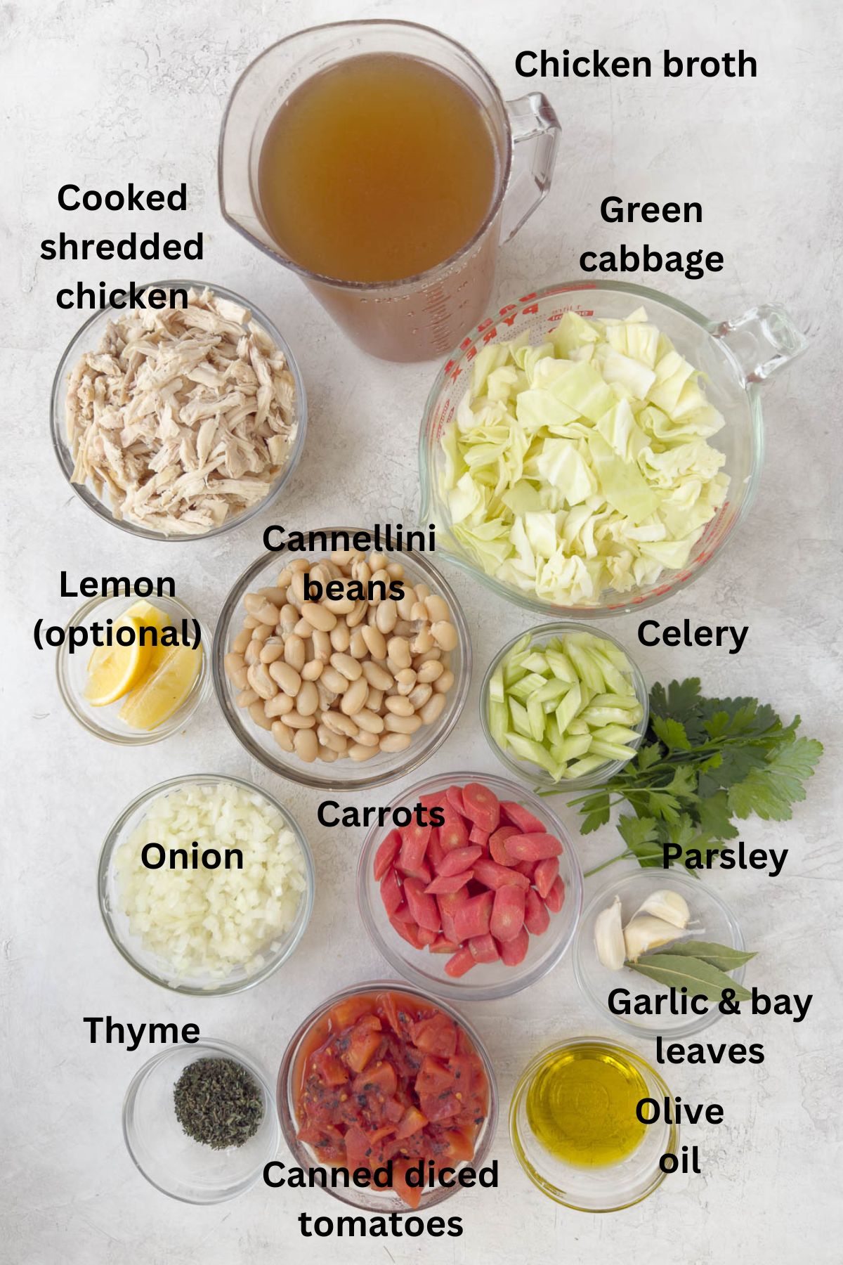 Ingredients for cabbage and chicken soup with broth, vegetables, herbs, oil, and tomatoes.