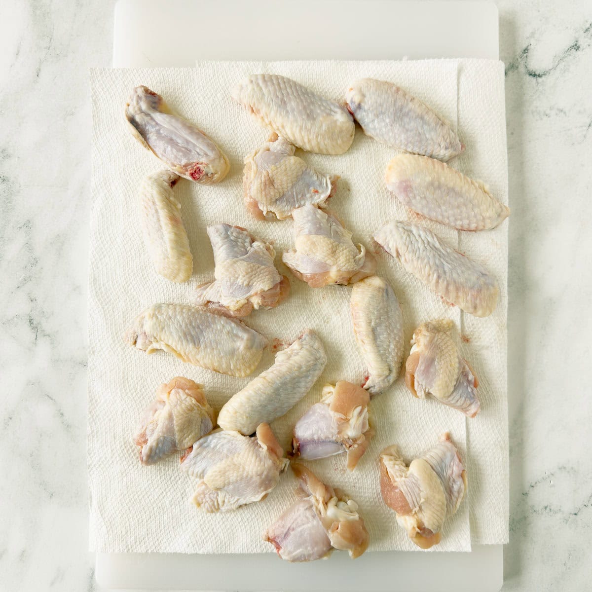 Drying chicken wings well on paper towels.