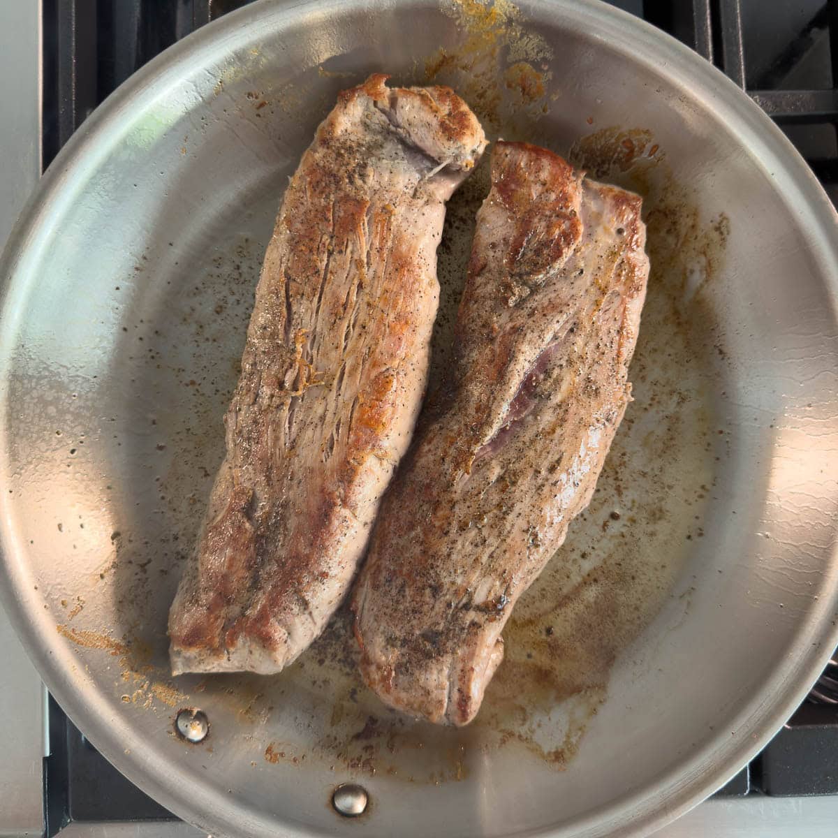 Browned pork tenderloin in a large fry pan.