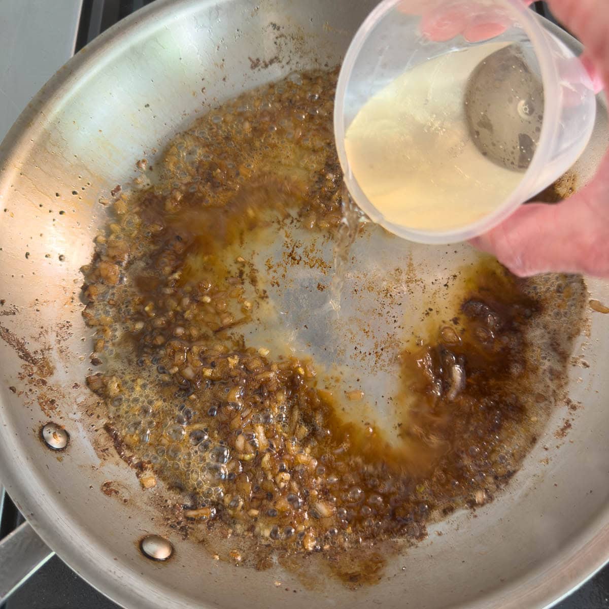 Deglazing a pan for pan sauce with white wine.