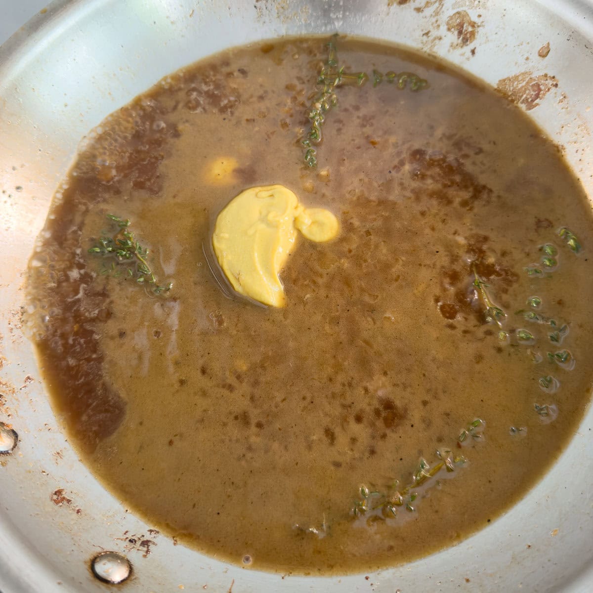 Adding golden Dijon mustard to a pan for thickening a sauce.