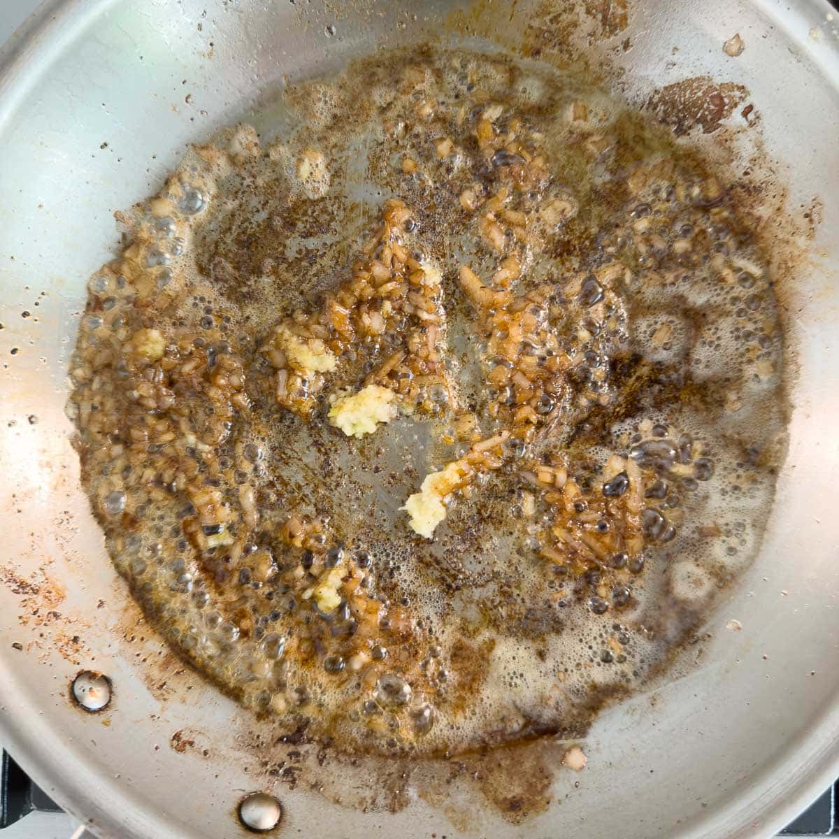 Adding chopped garlic to a pan with sautéed shallots in butter.