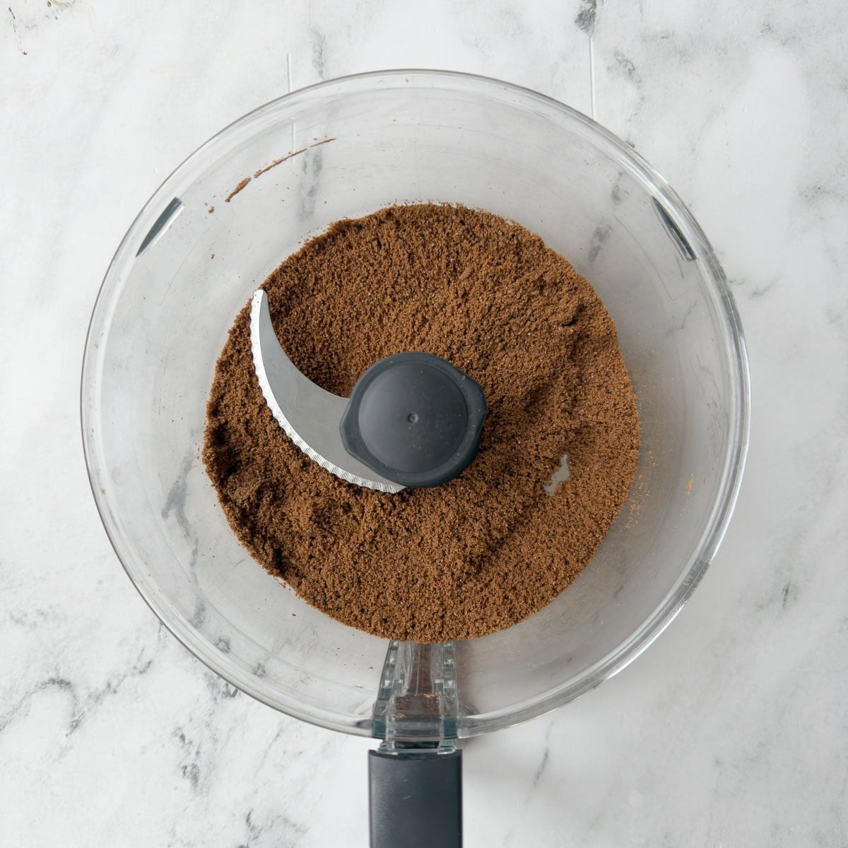 Crushed chocolate cookie crumbs in a food processor workbowl.