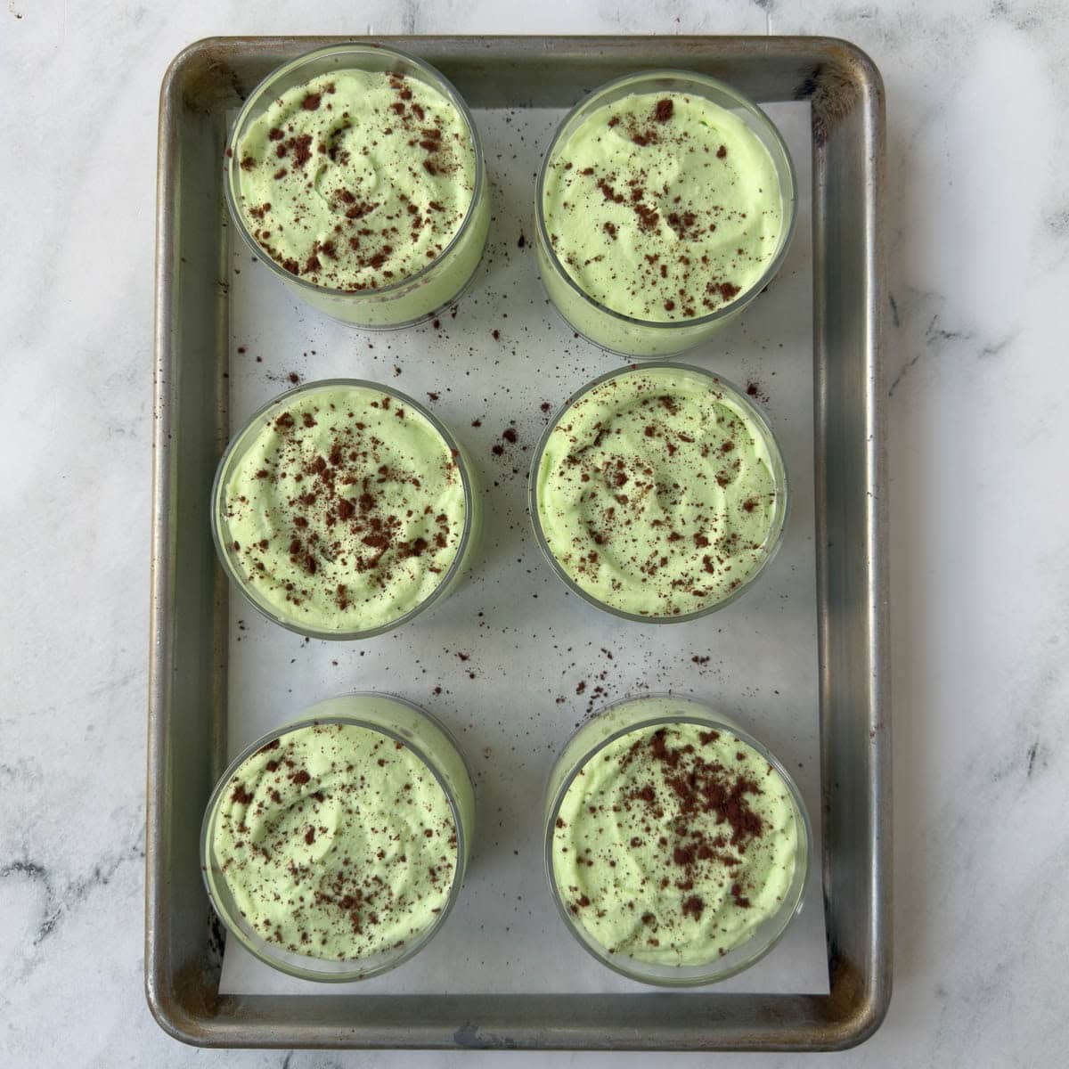 Six finished grasshopper pie cups sprinkled with cookie crumbs on top.