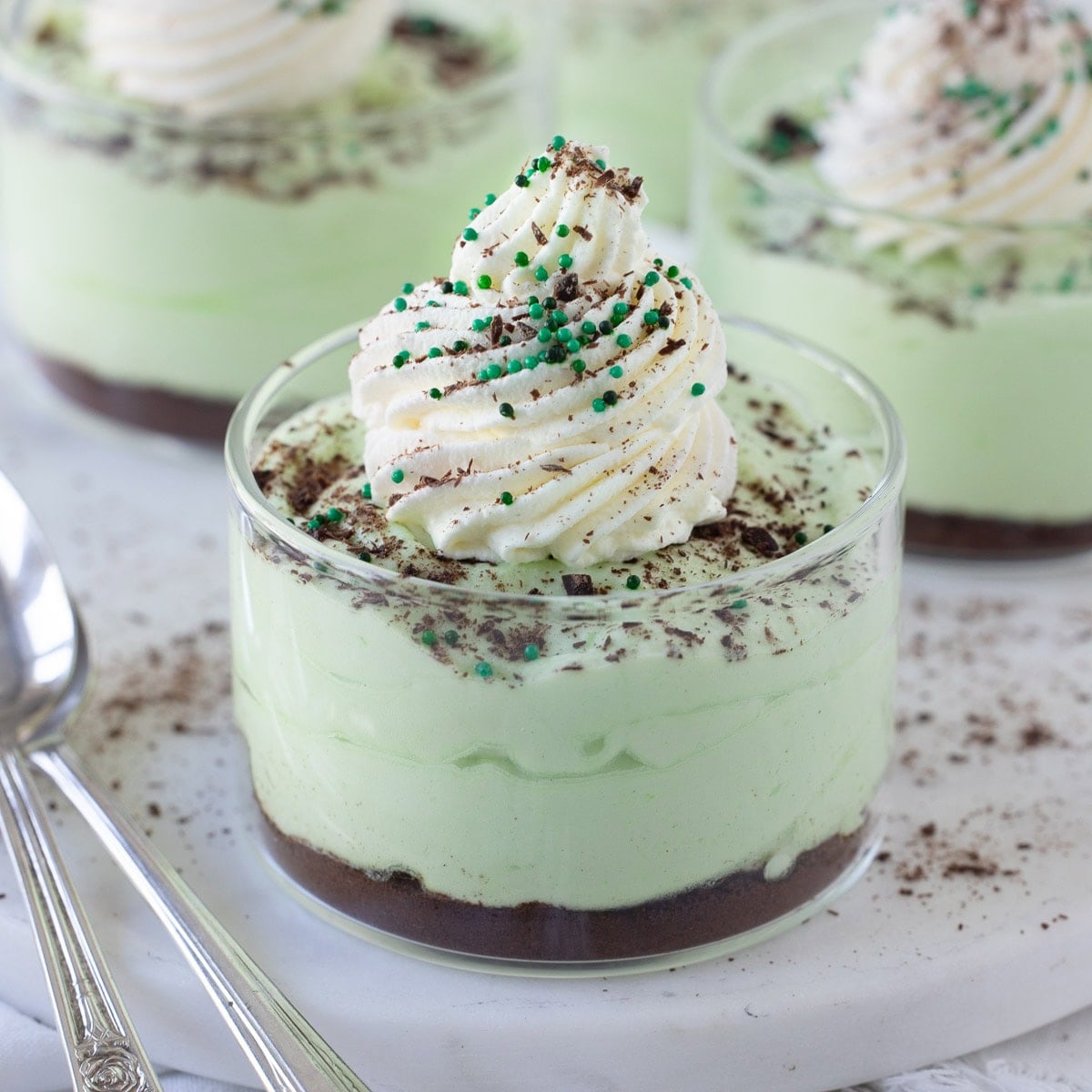 Green creme de menthe grasshopper pie mousse in glass ramekins with chocolate cookie crumbs.