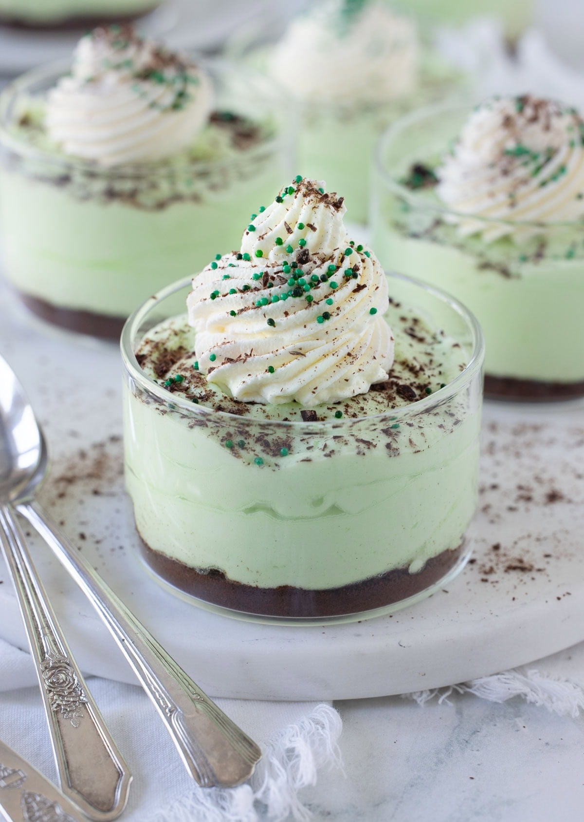 Grasshopper pie cups, pale green chocolate mint mousse in glass cups with crushed cookie bottoms.