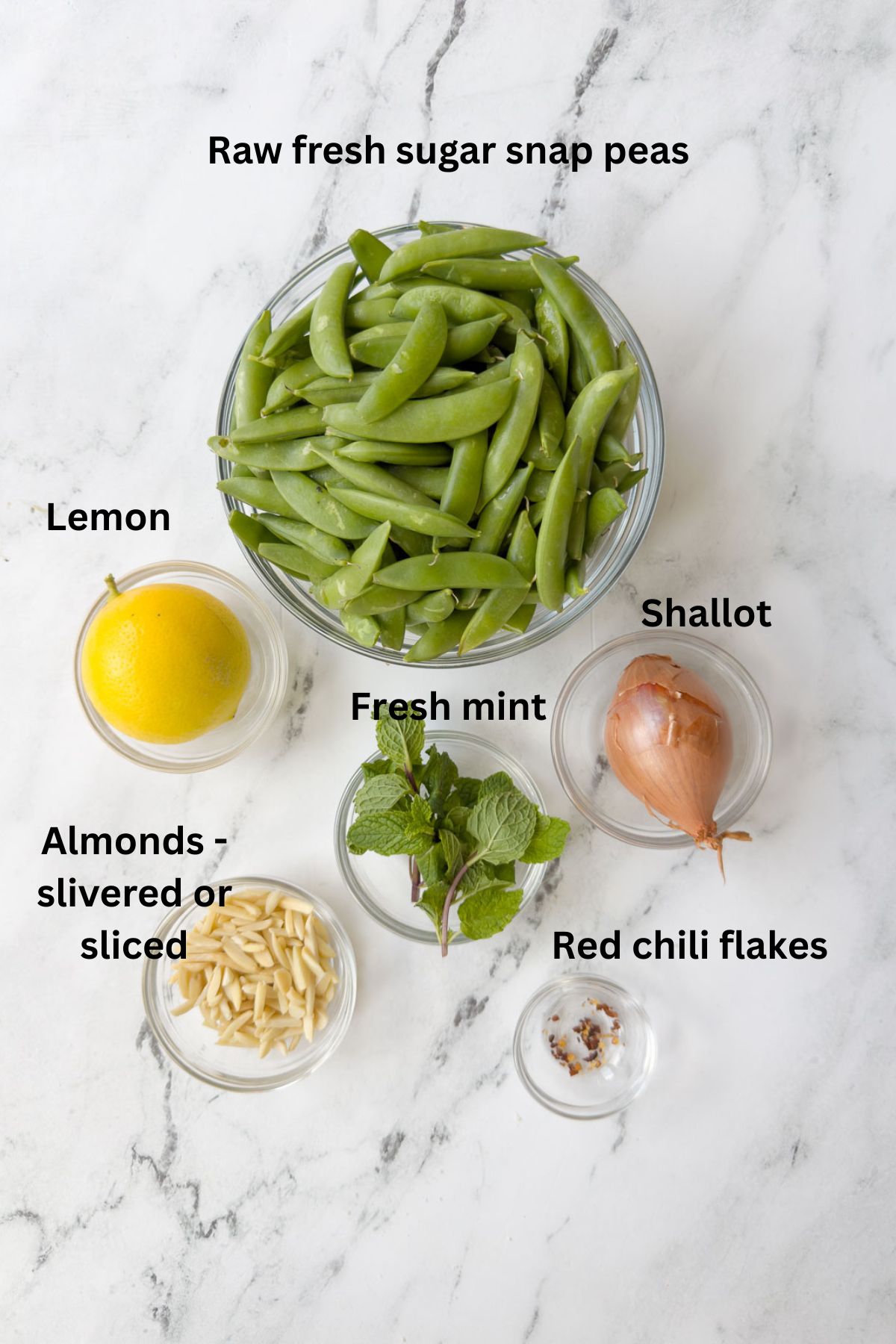 Ingredients for a fresh sugar snap pea salad with shallot, lemon, and mint.