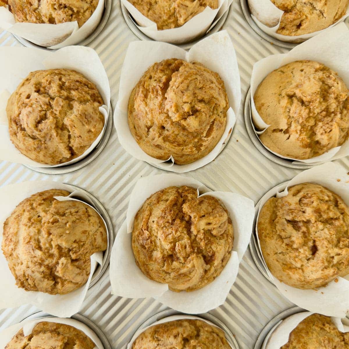 Baked cinnamon roll muffins in the muffin pan cooling.