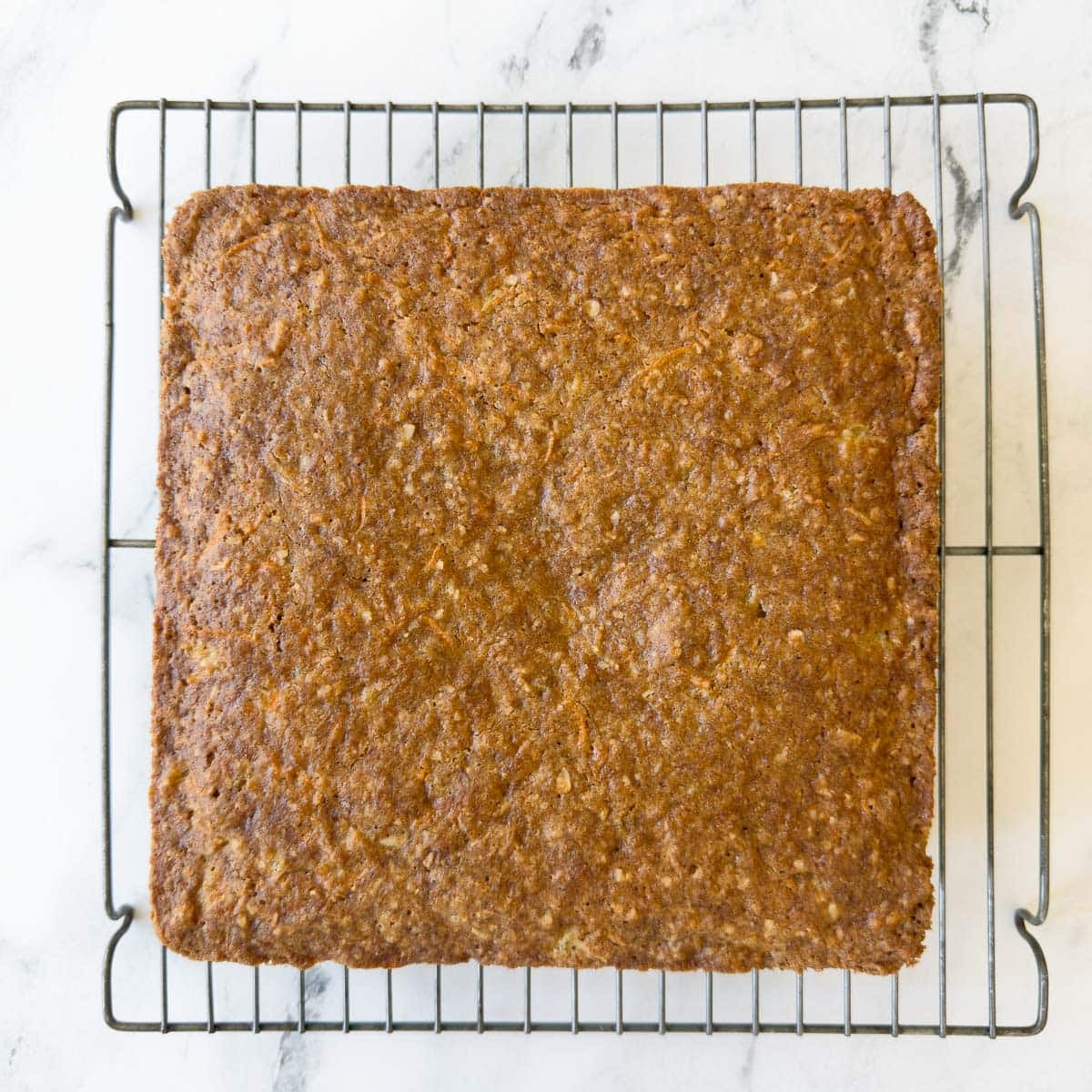 Baked gluten free carrot cake on a cooling rack.