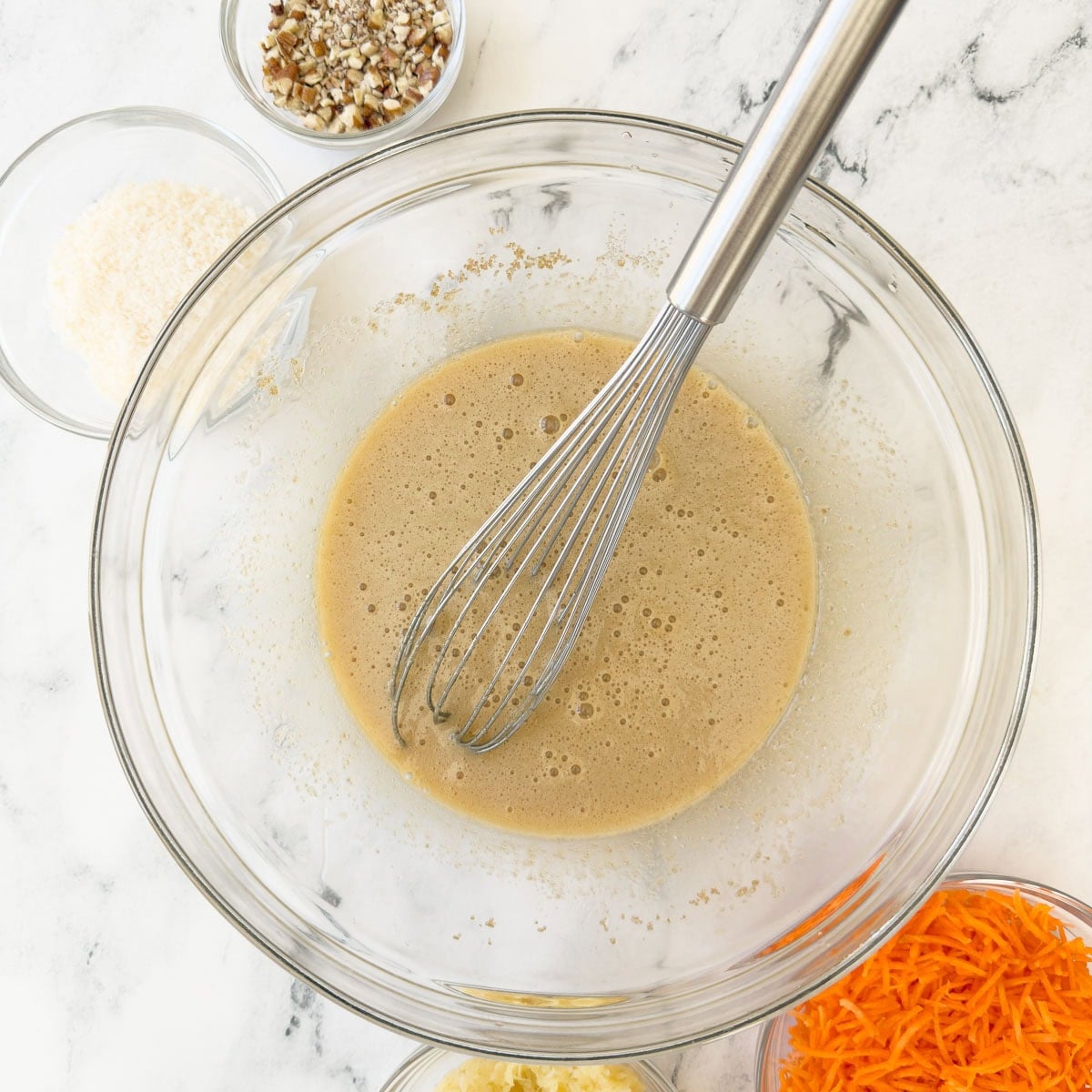 Mixing wet ingredients for cake batter in a glass bowl.