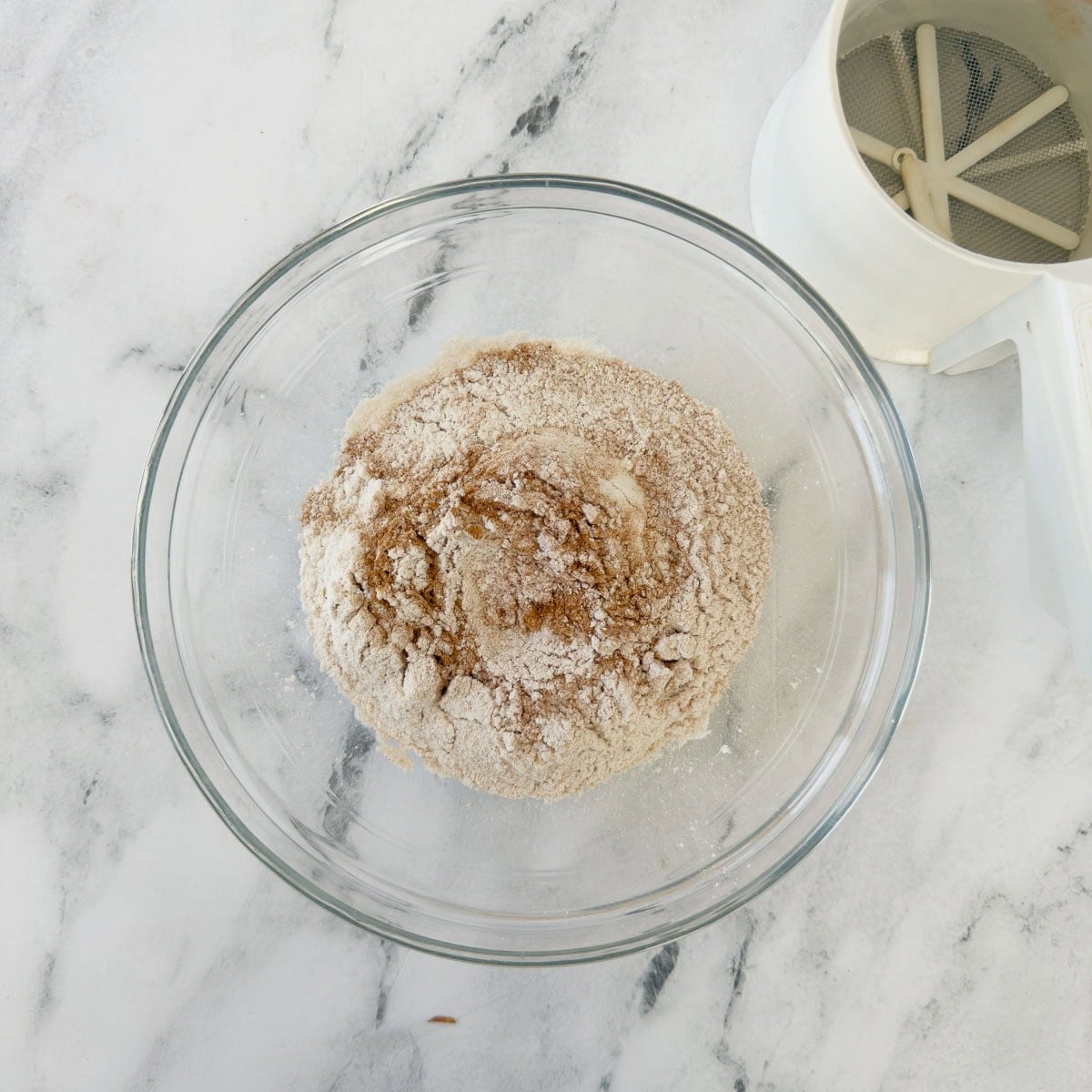 Sifted flour and spice in a bowl with the sifter nearby.