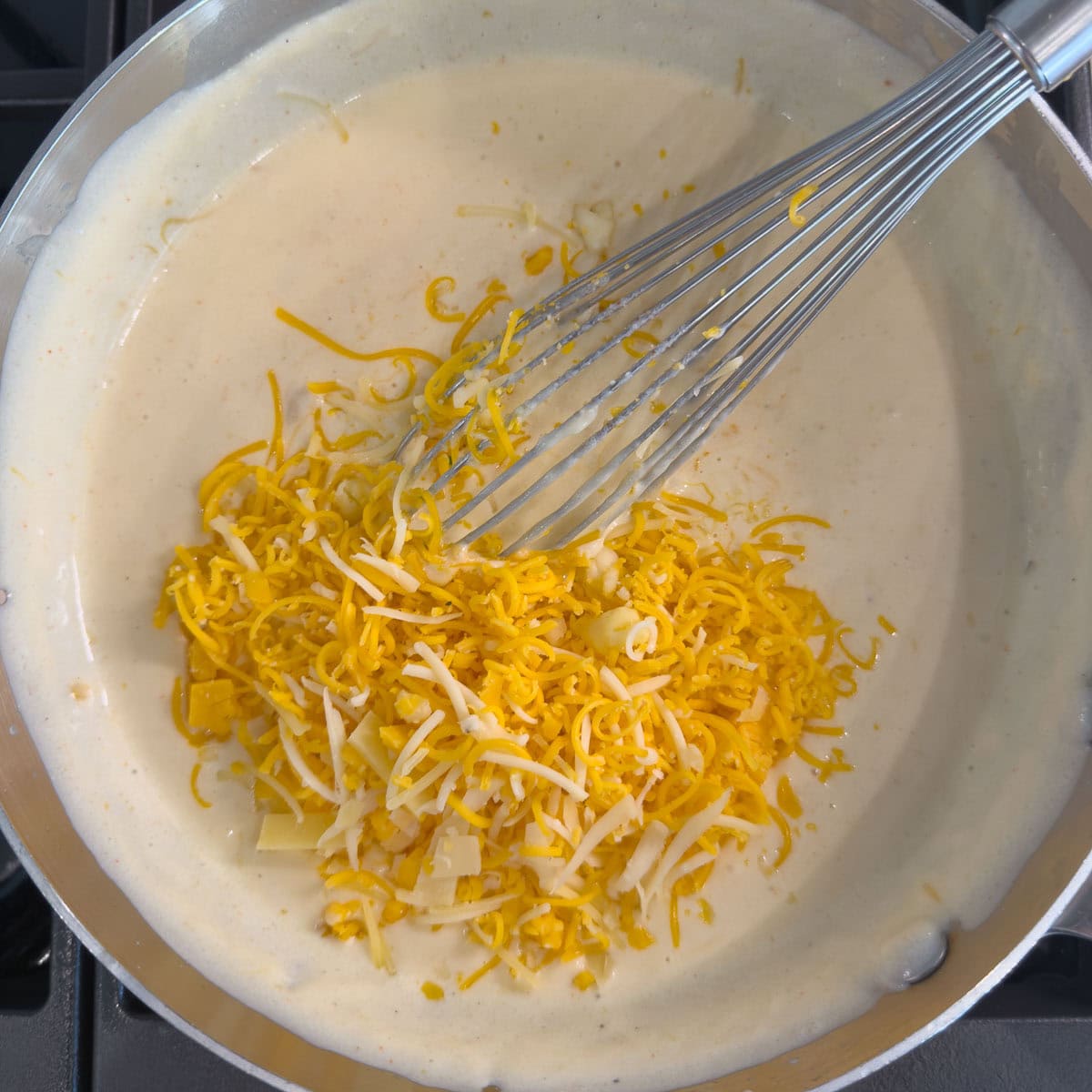 Adding grated cheese to a white sauce in a pot, to make cheese sauce.
