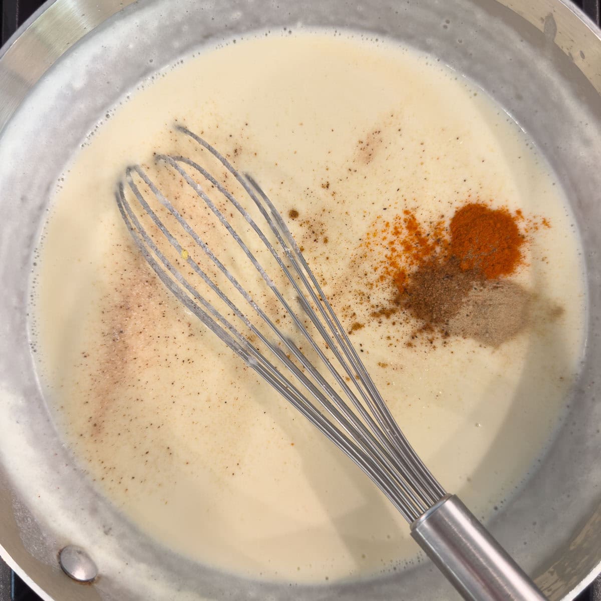 Adding spices to a white sauce, paprika, nutmeg, and white pepper.