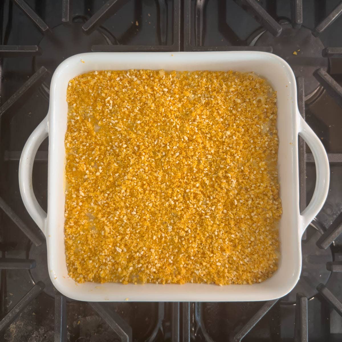 gluten-free mac and cheese with the parmesan topping in a square baker, ready to bake or broil.