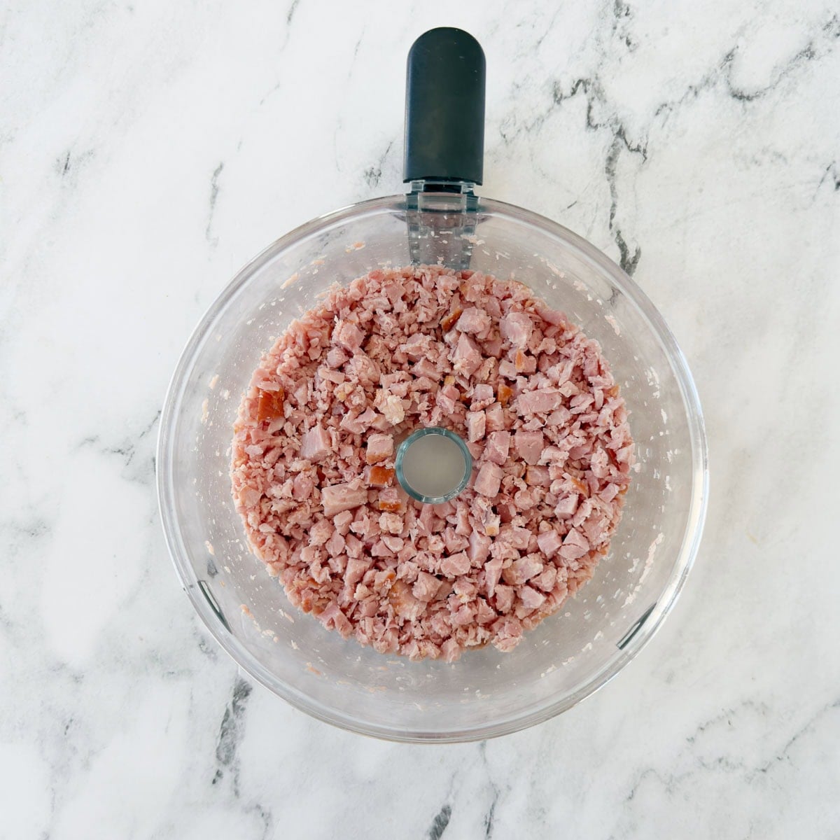 Chopped ham in a food processor workbowl.