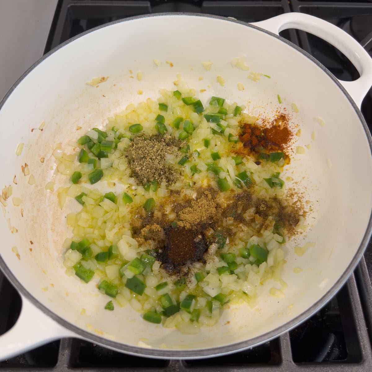 Spices, herbs, onion, and jalapeno cooking in olive oil