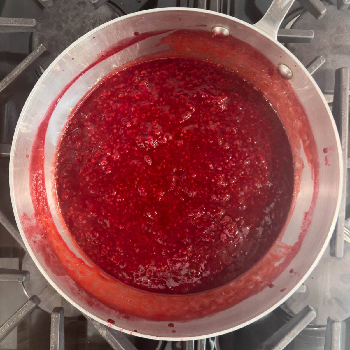 A fiished pot of chunky bright red raspberry sauce ready to serve or chill.