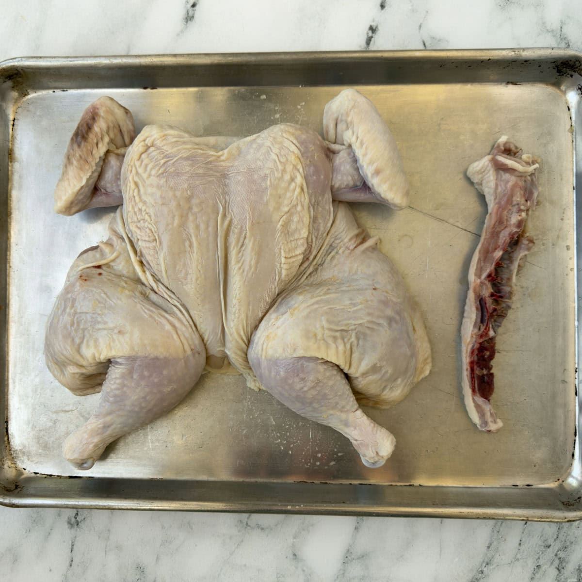 A flattened chicken top side up after removing the backbone.