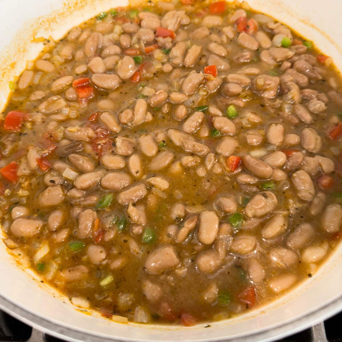 A pot of simmer broth charro beans with tomatoes and jalapeno.