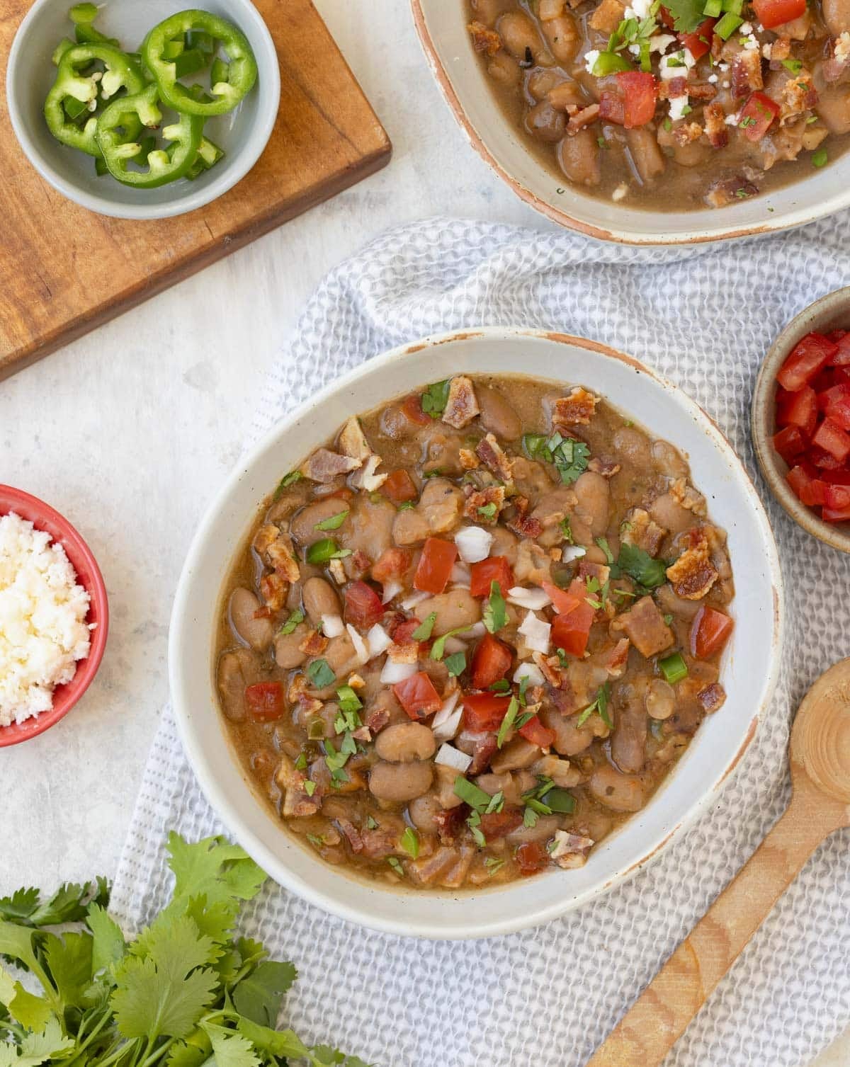 Bowls of charro beans, pinto beans Mexican-style with bacon, jalapeno, tomato, onion, and cilantro.