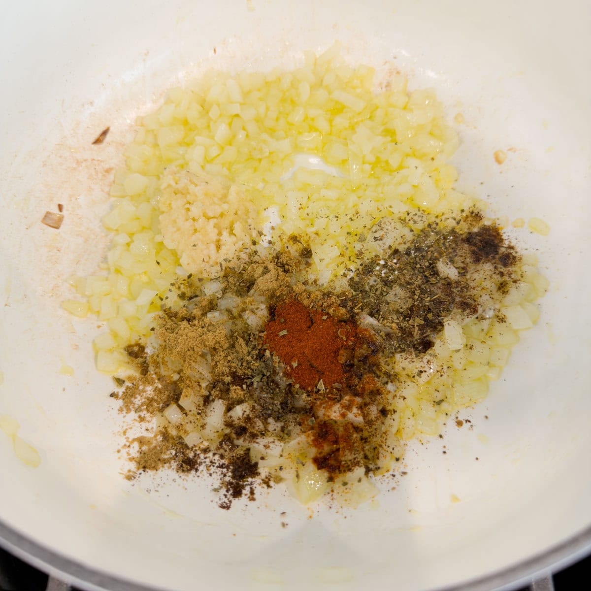 Spices and dried herbs added to a pot of softly cooked onions for charro beans base.