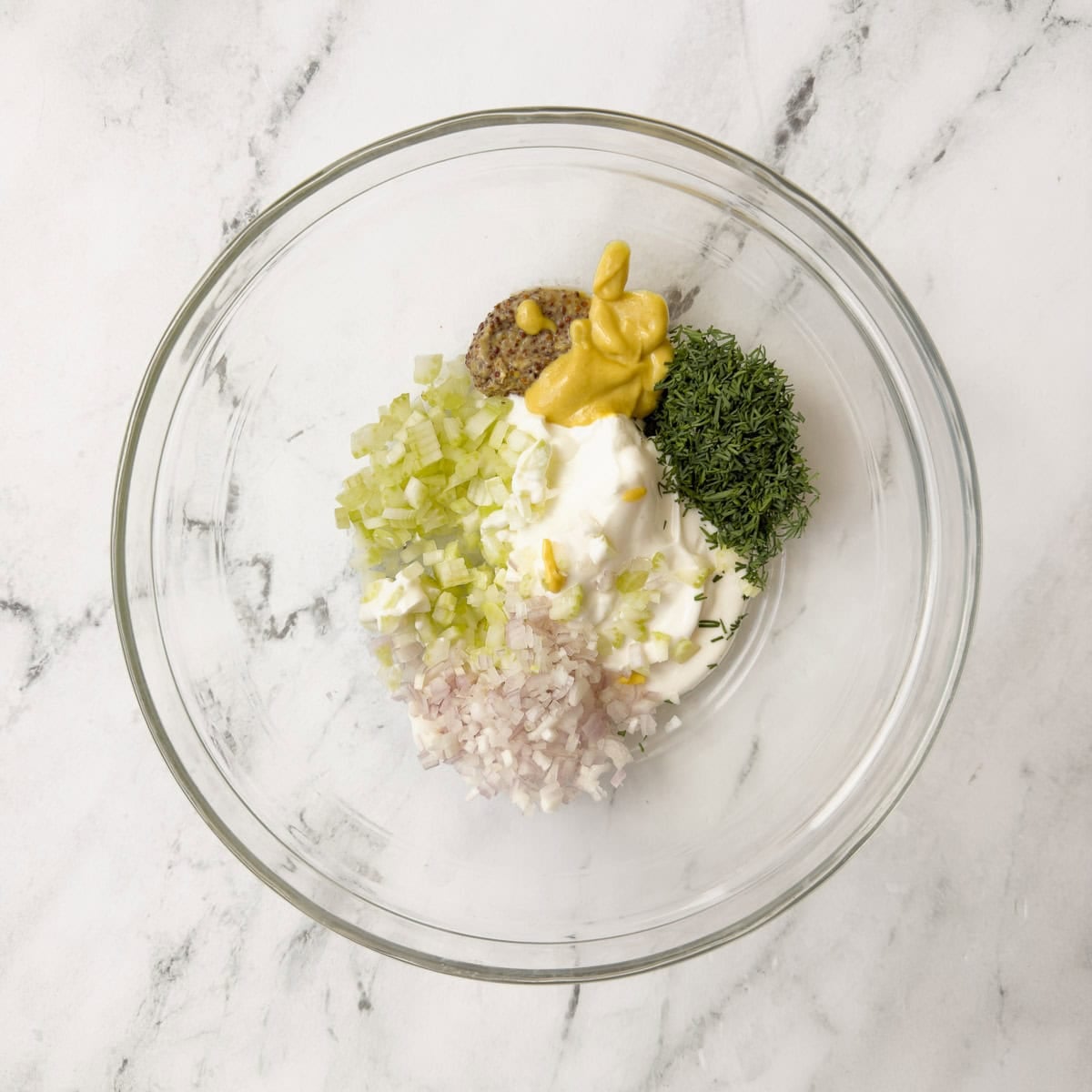 Egg salad dressing ingredients in a glass bowl.