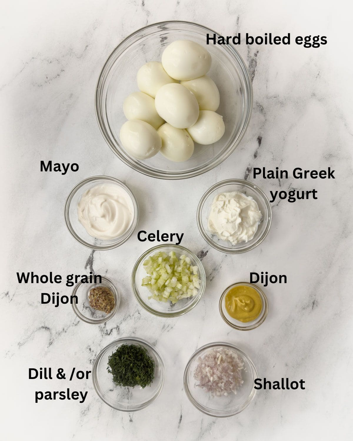 Healthy egg salad ingredients in prep bowls on a counter.