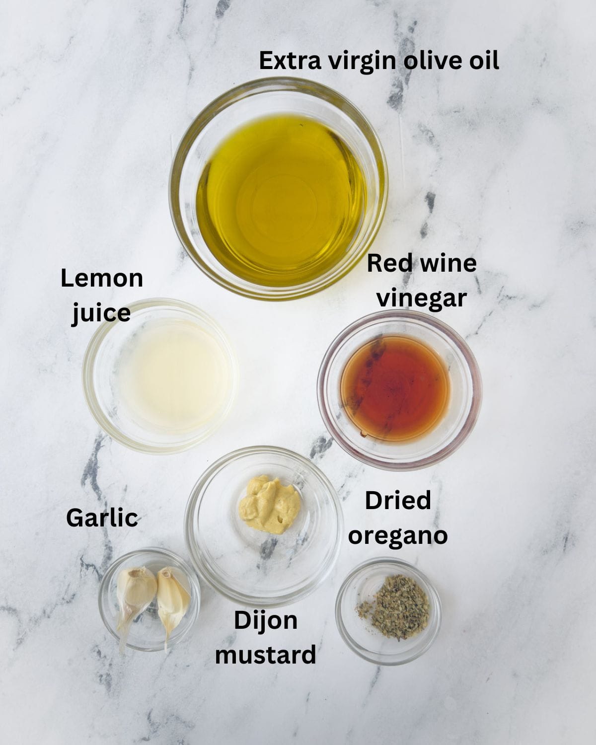 Olive oil, lemon juice, vinegar, garlic, mustard, oregano for a Greek salad dressing in prep bowls