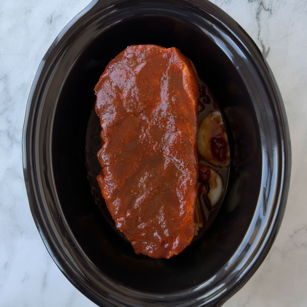 A glossy, saucy pork shoulder ready for slow cooking bbq pulled pork.