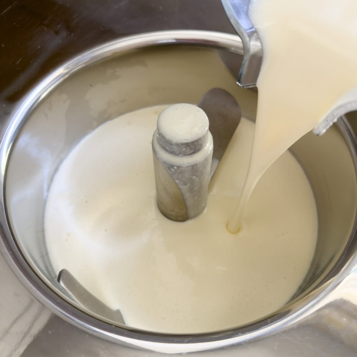 Ice cream base pouring into an ice cream maker for churning.