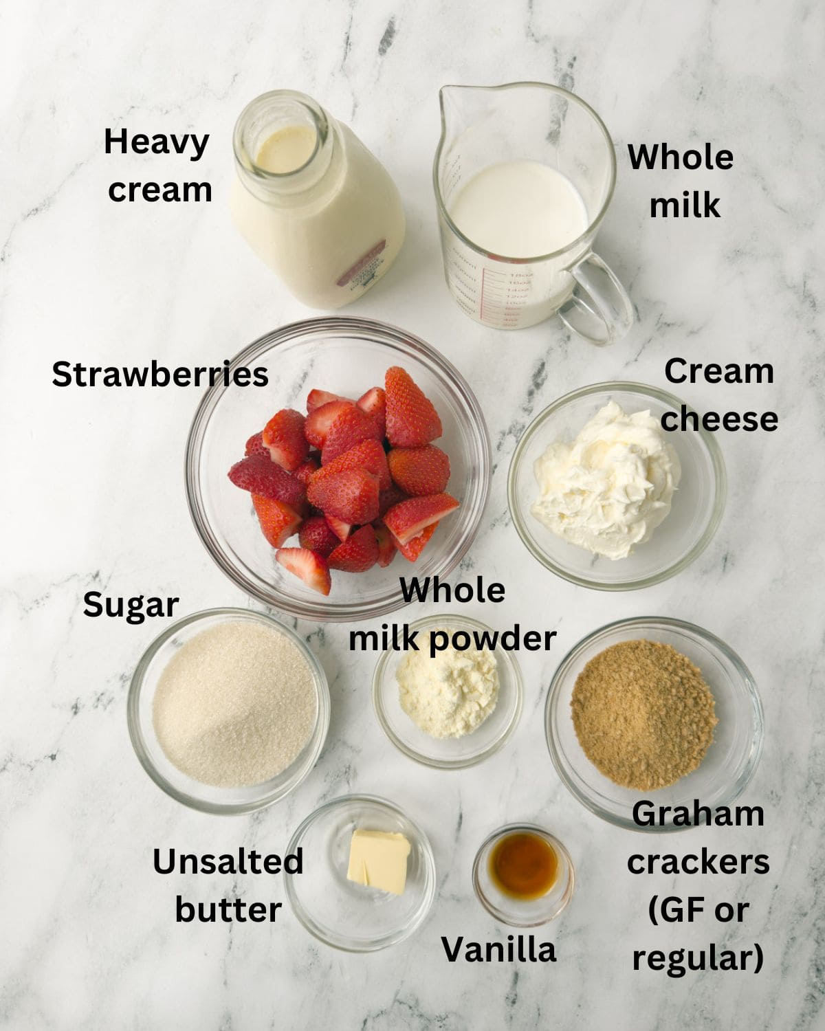 Ingredients for strawberry cheesecake ice cream in prep bowls on a counter.