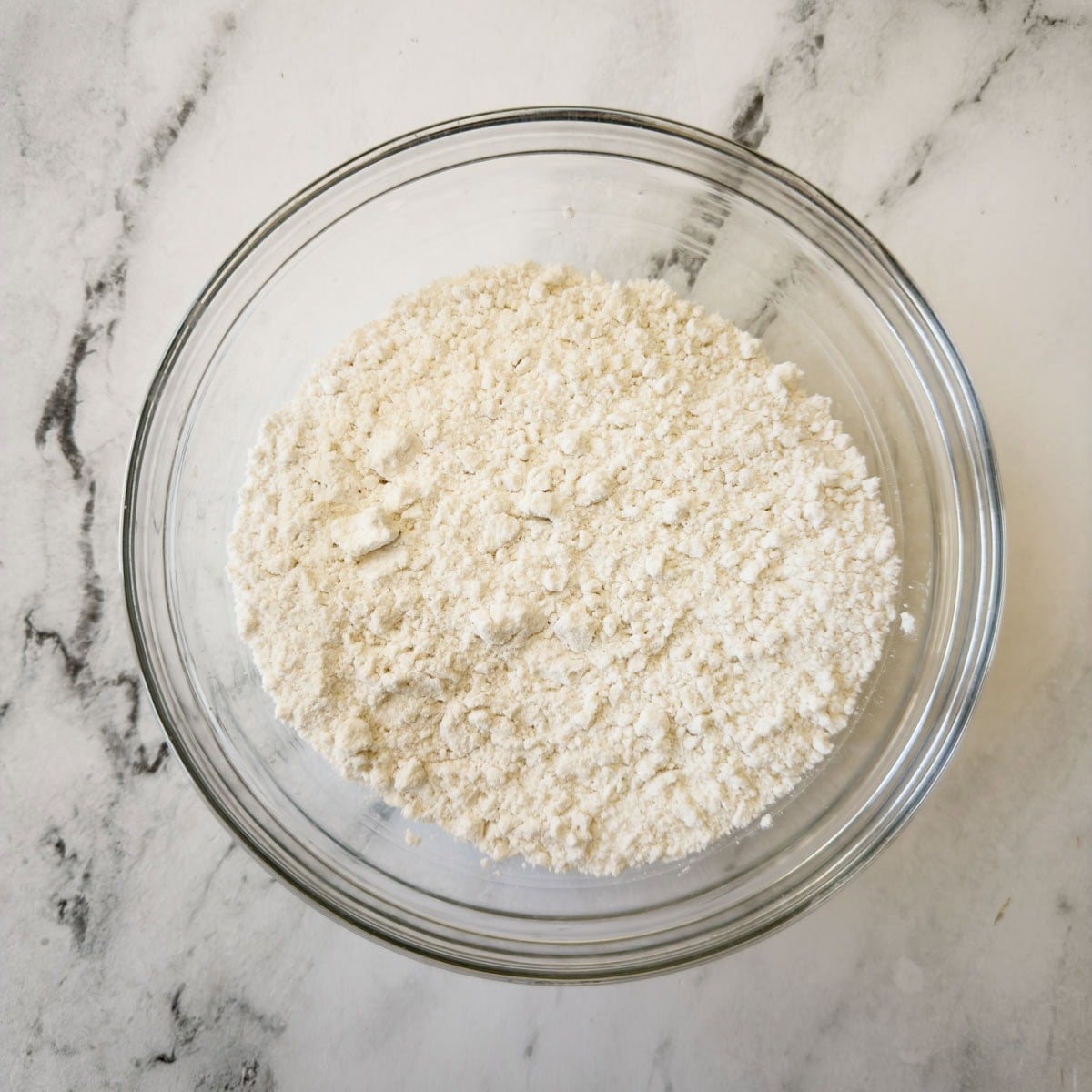 Sifted flour and other dry ingredients in a glass bowl for baking a cake.