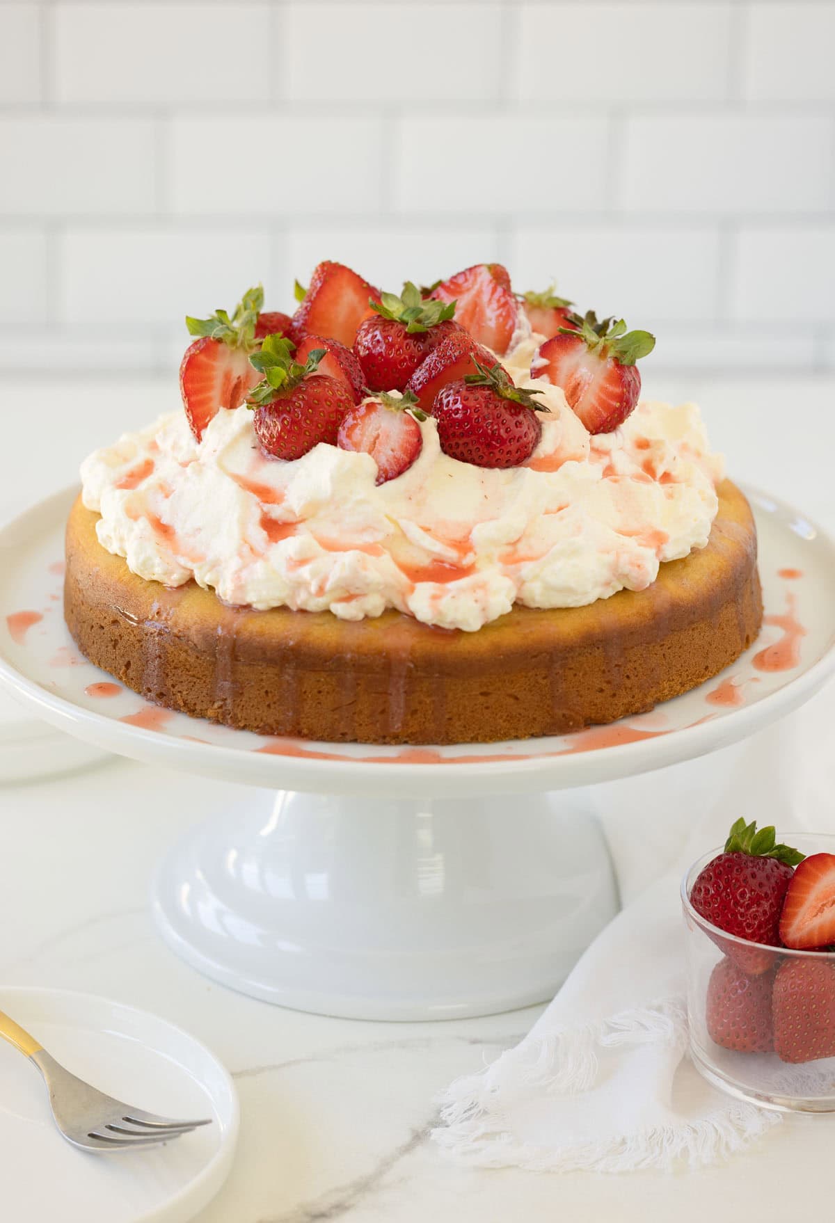 A strawberry shortcake cake piled high with whipped cream and topped with juicy red strawberries.