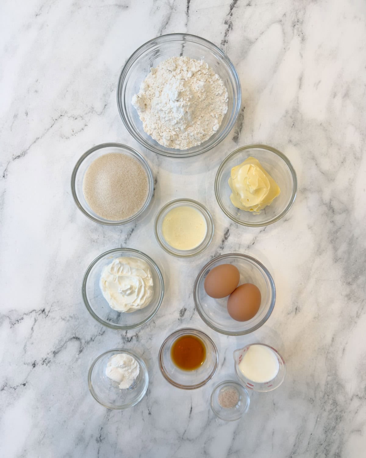 Ingredients for a vanilla shortcake, cake style, in prep bowls on marble counter.
