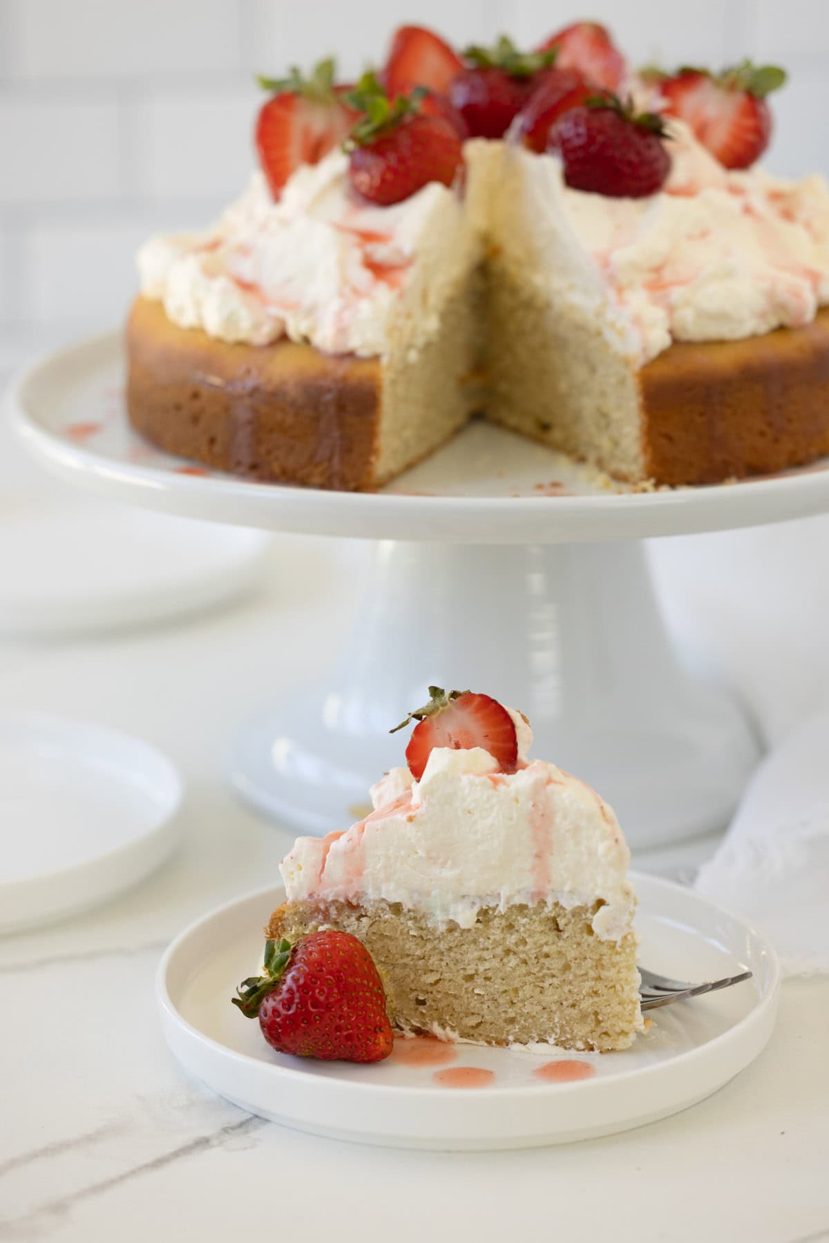 A slice of strawberry shortcake cake with whipped cream and strawberries.
