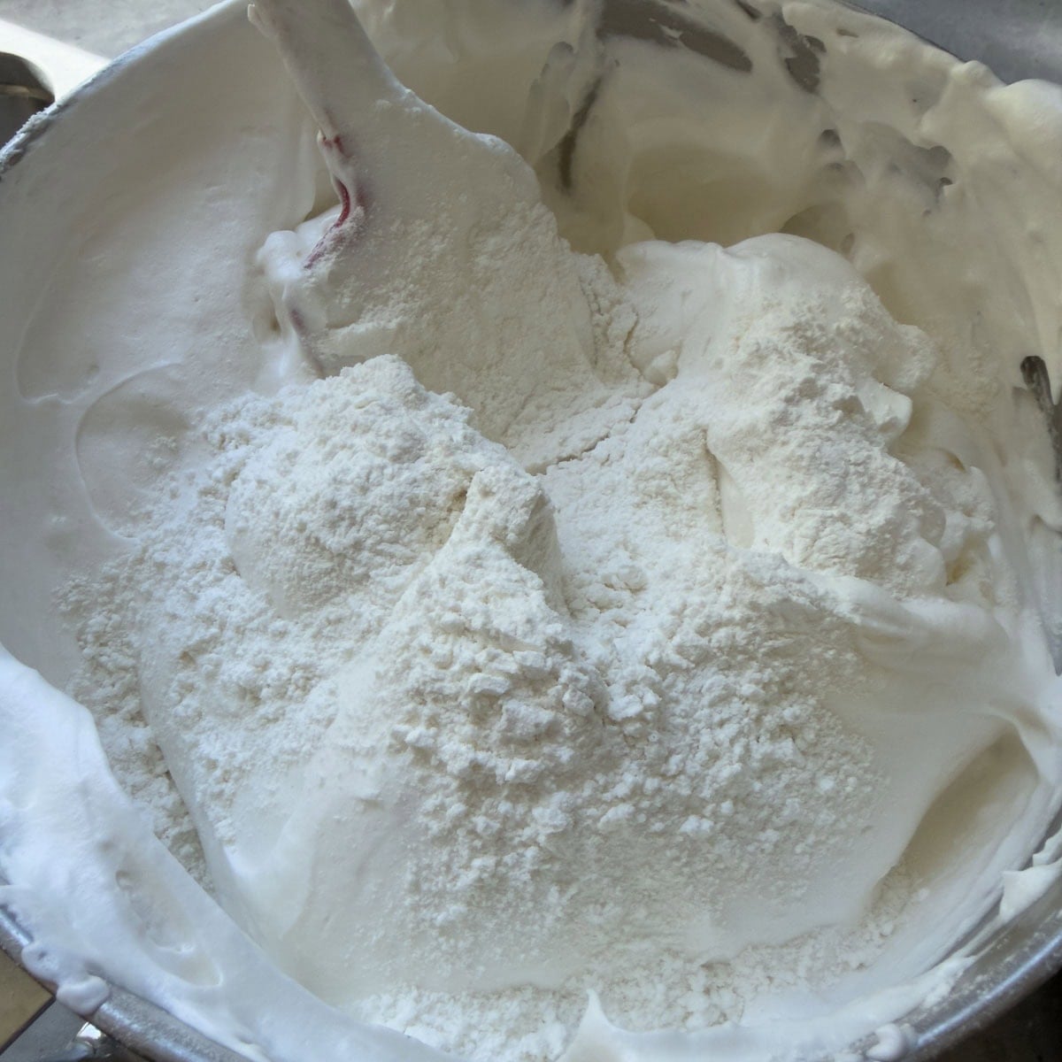 Folding flour into angel food cake batter by hand.