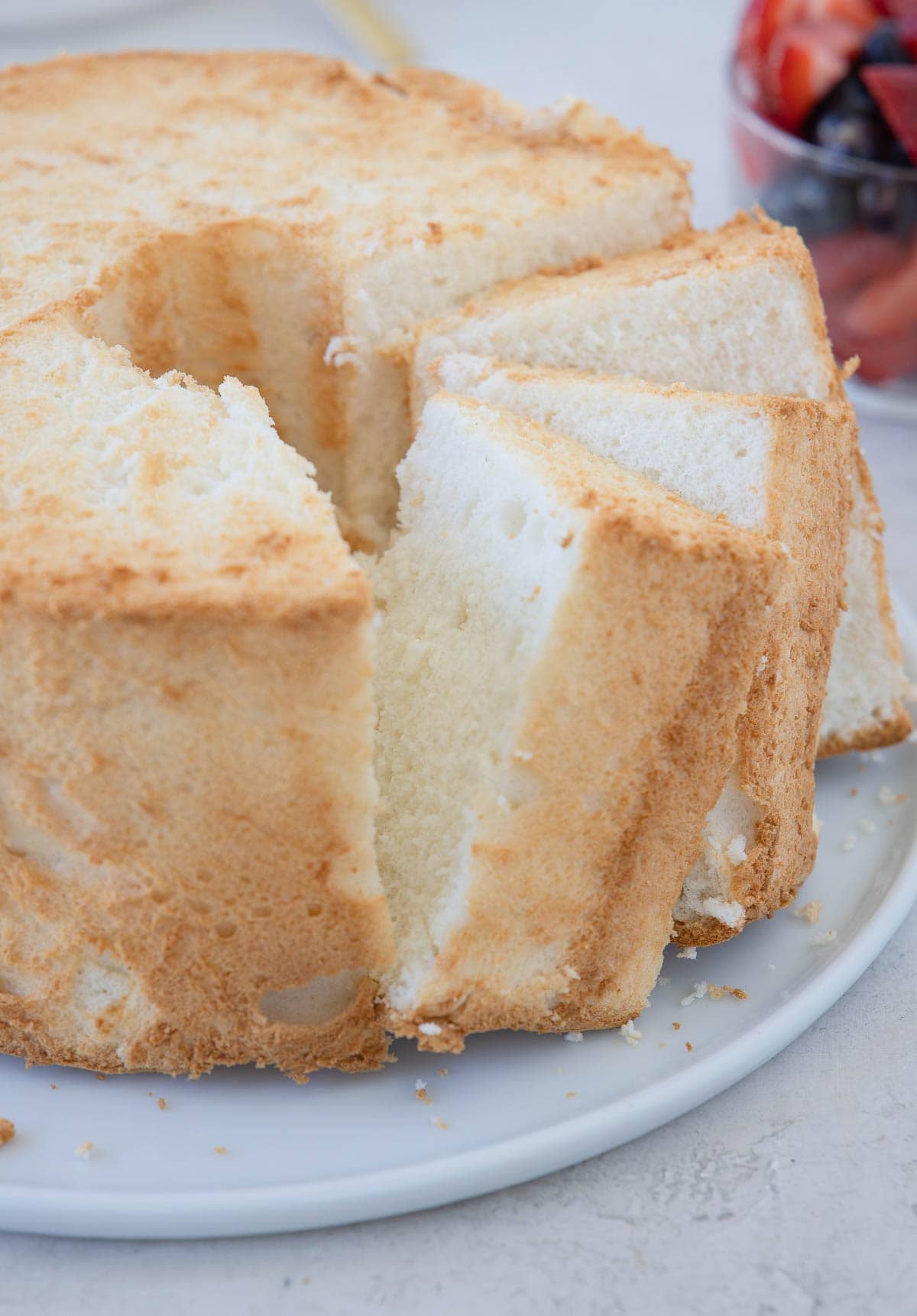 Gluten angel food cake with tilted slices on a cake plate.