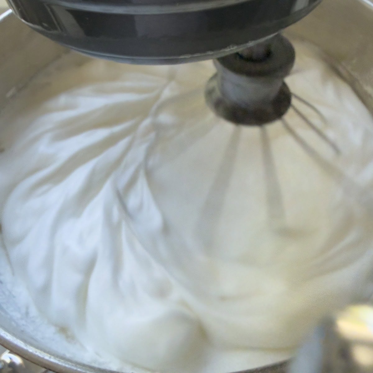 Whipping egg whites in a standing mixer bowl with whip attachment.