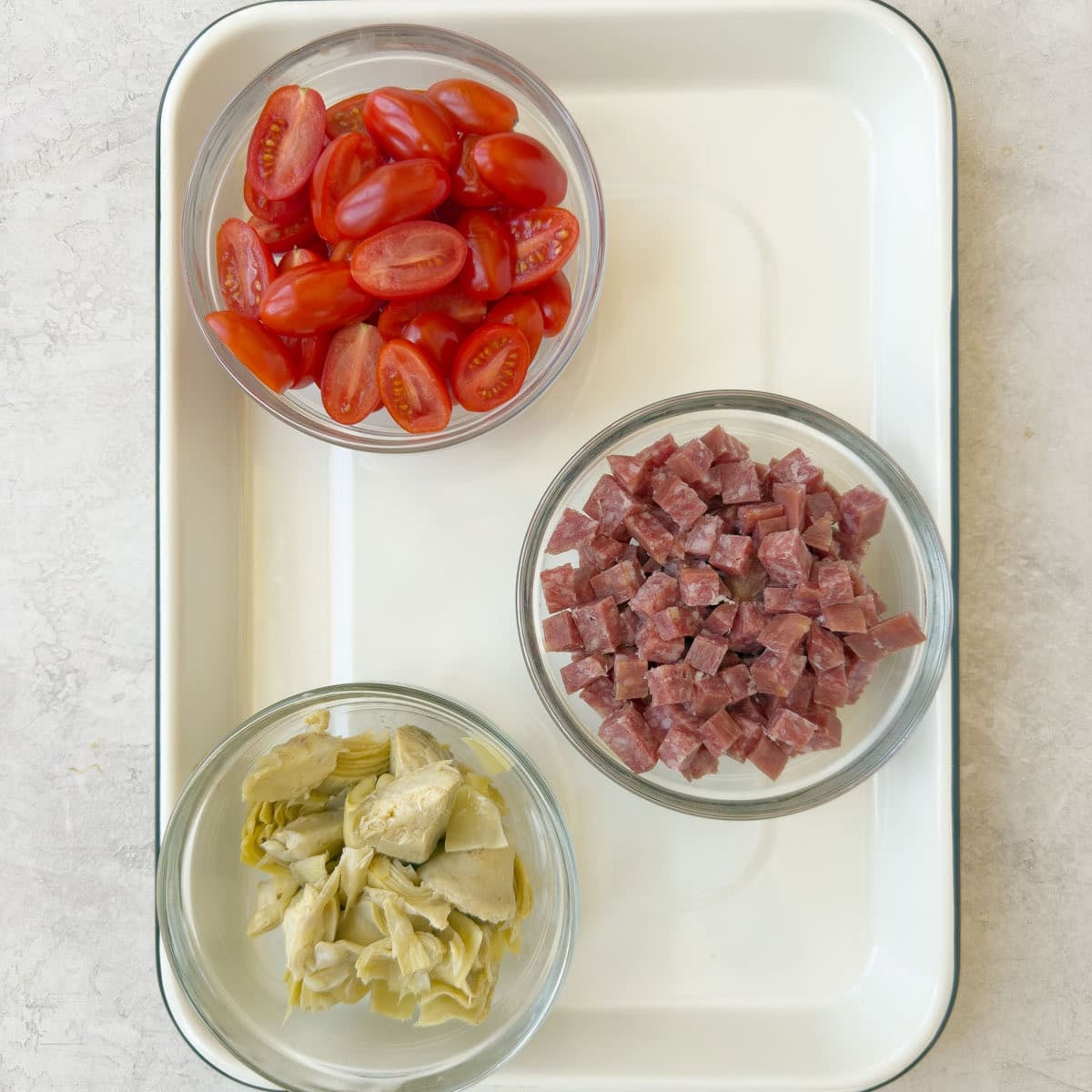 Halved tomatoes, diced salami, and chopped artichoke hearts for an antipasto pasta salad.