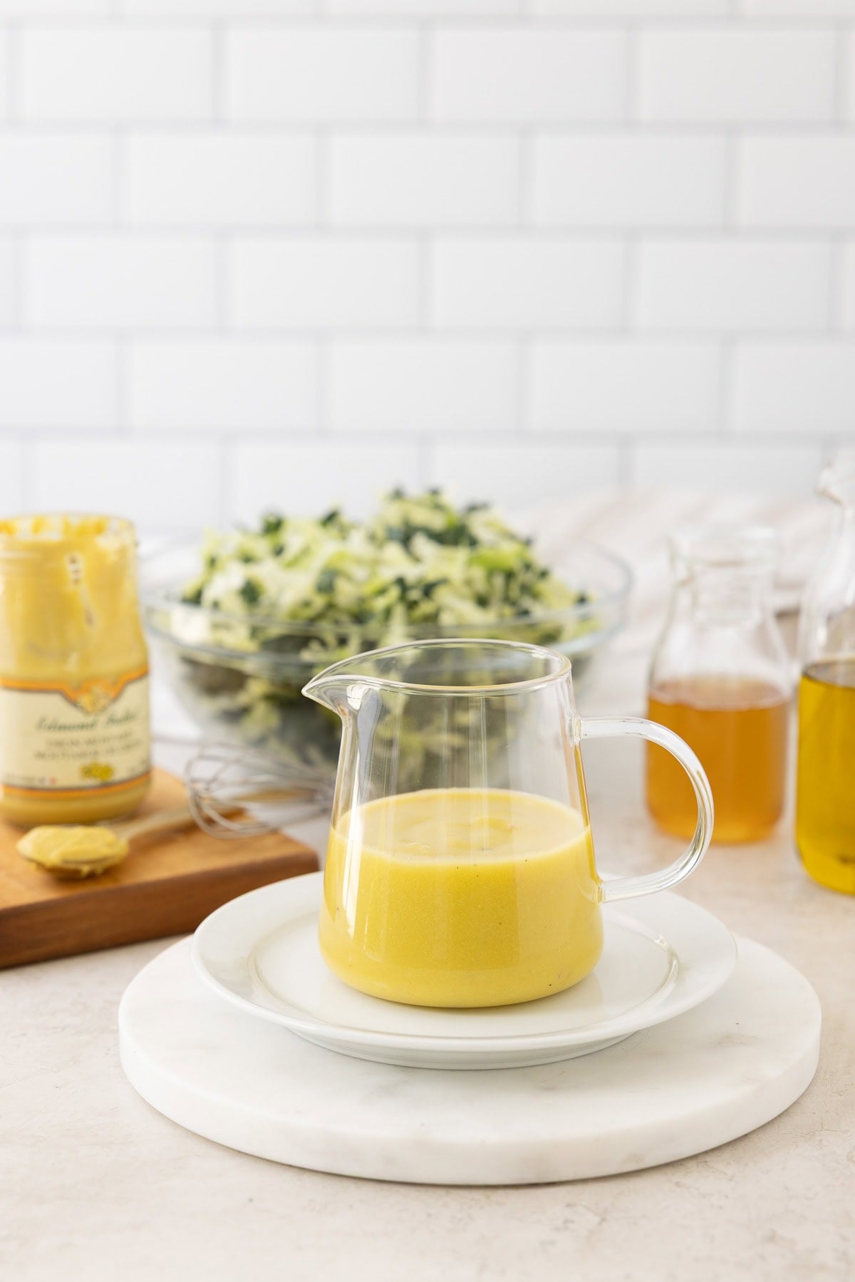A mini glass pitcher of creamy golden dijon mustard vinaigrette.