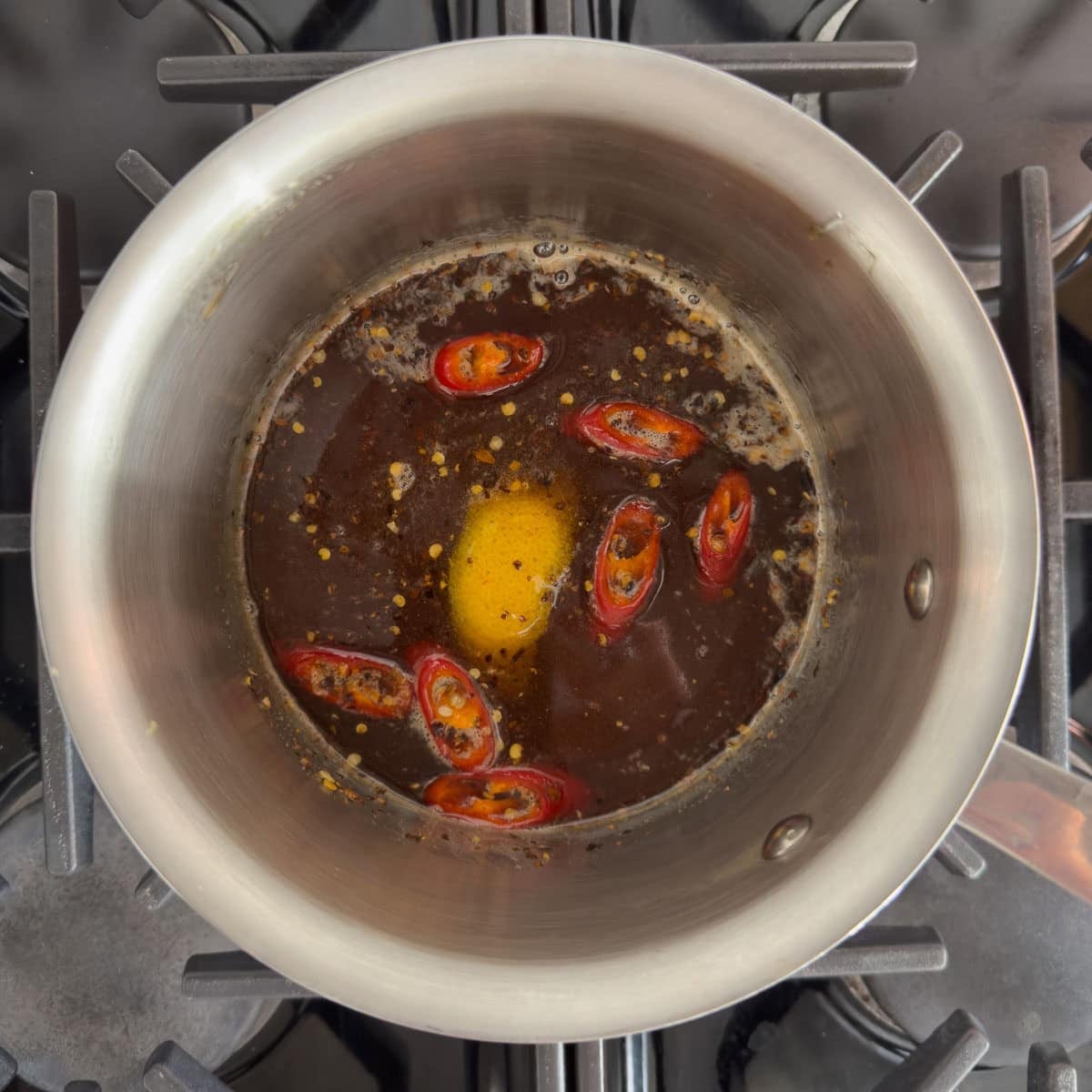 Honey infusing in a pan with red chiles, red chile flakes, and orange peel.