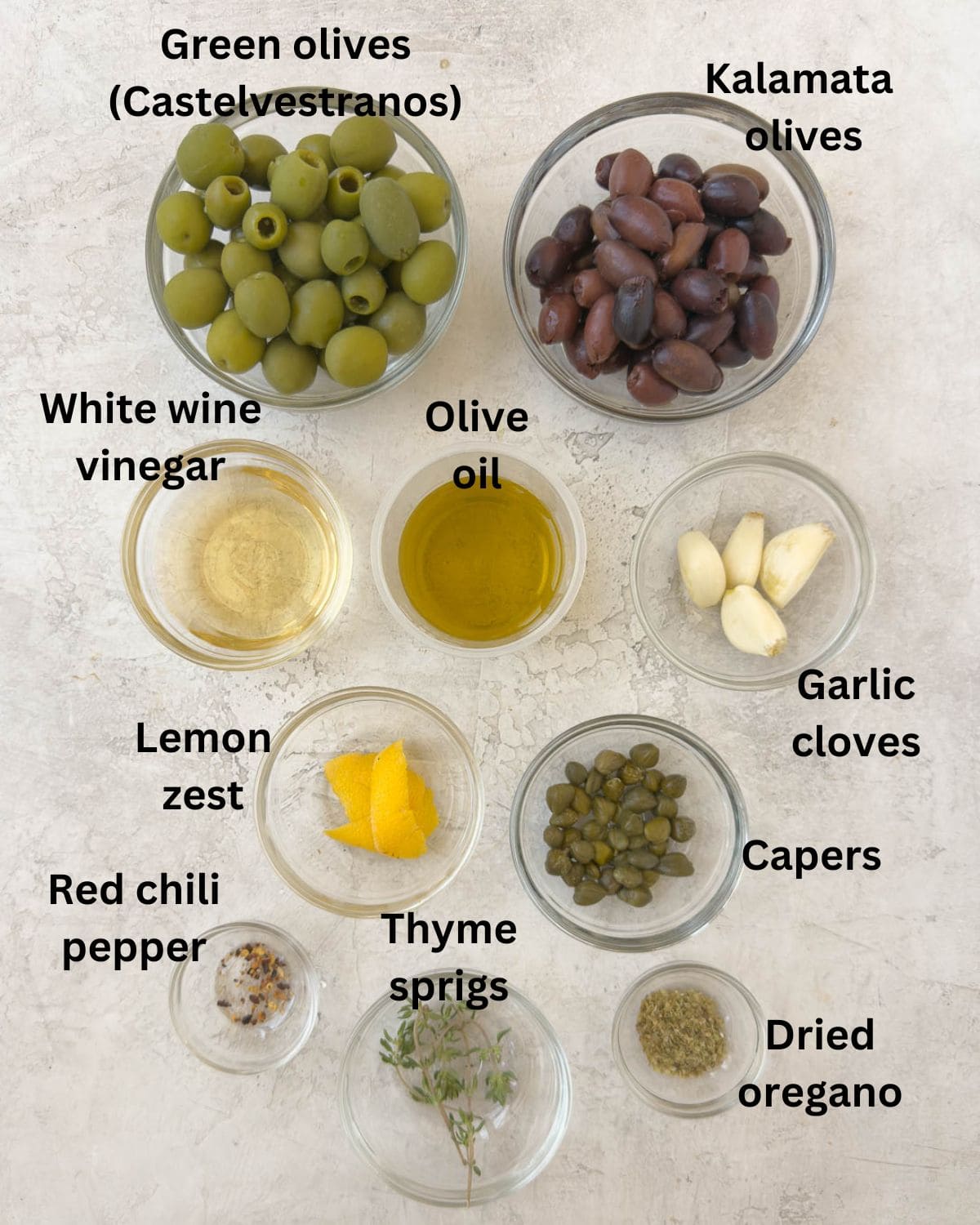 Ingredients for marinated olives with oil, herbs, garliccapers and vinegar.