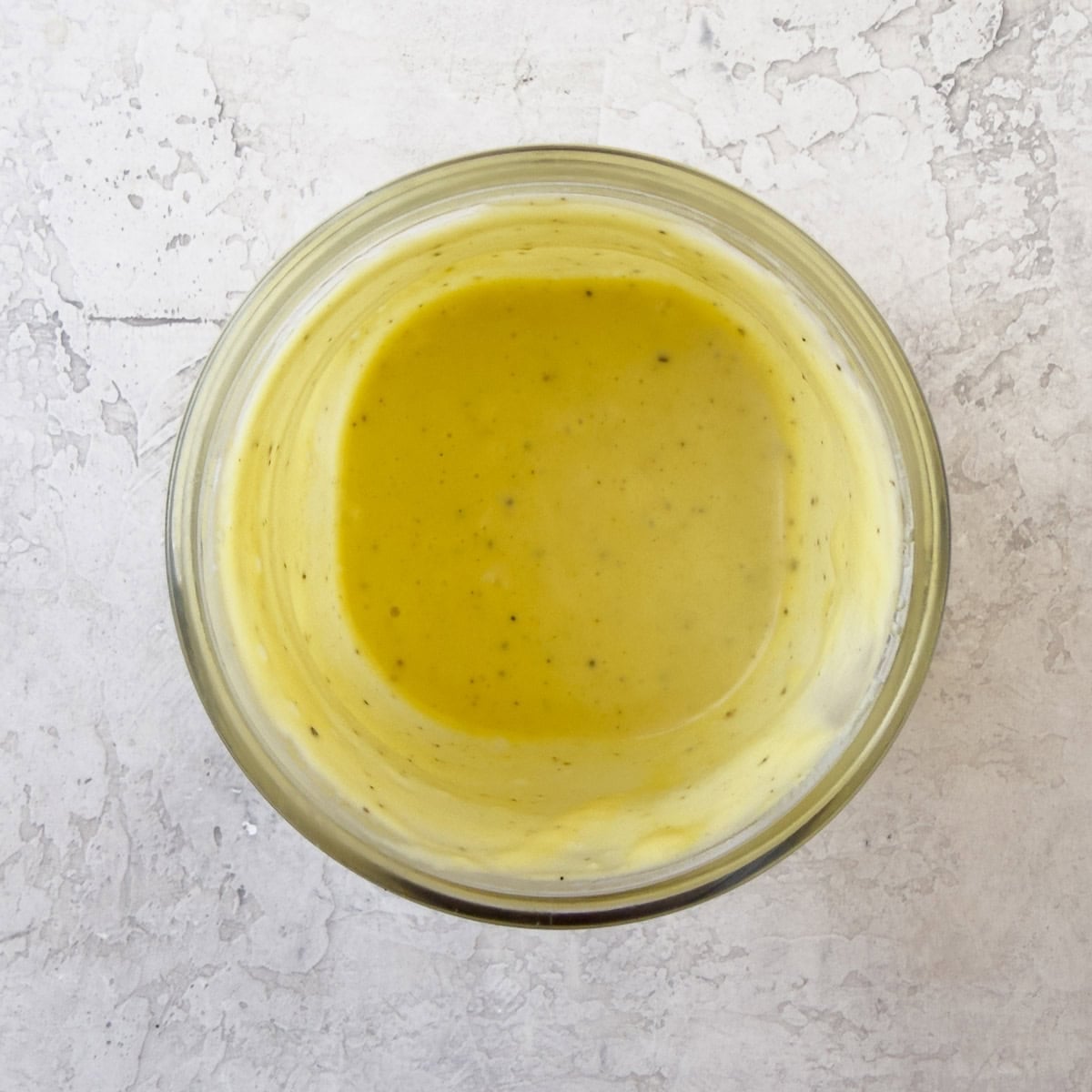 A bight golden yellow creamy vinaigrette in a jar.