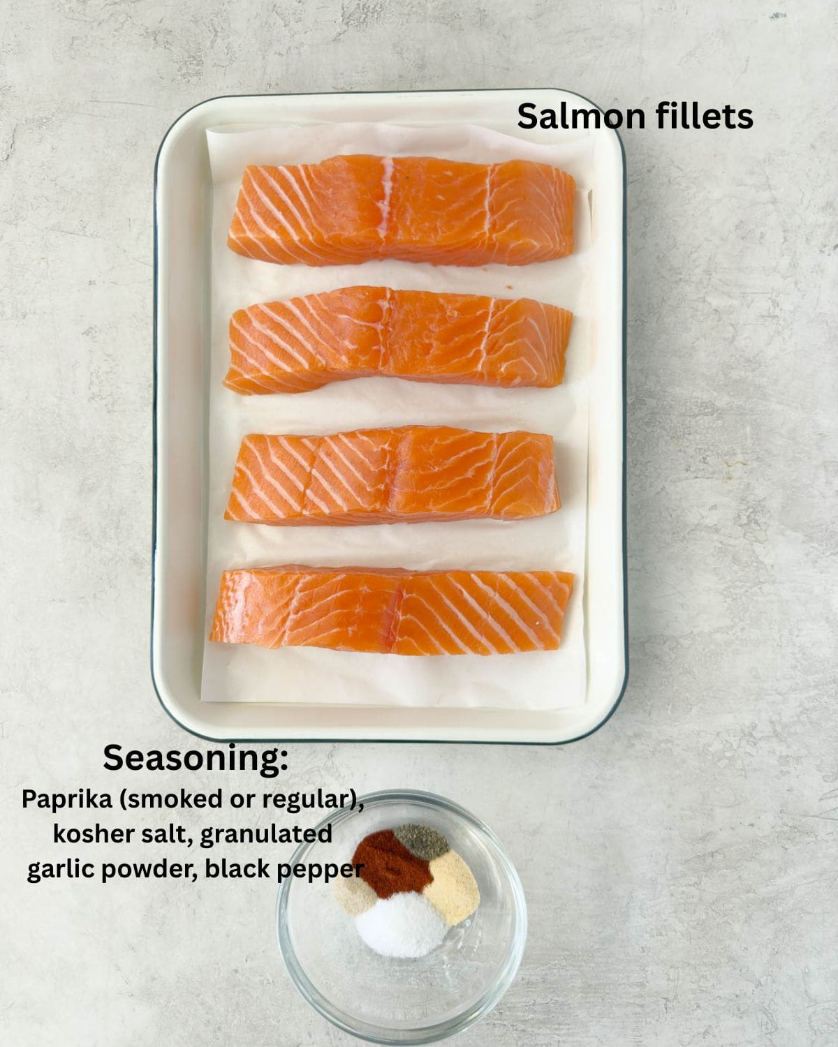 Four bright orange fresh salmon fillets with seasonings on a tray.