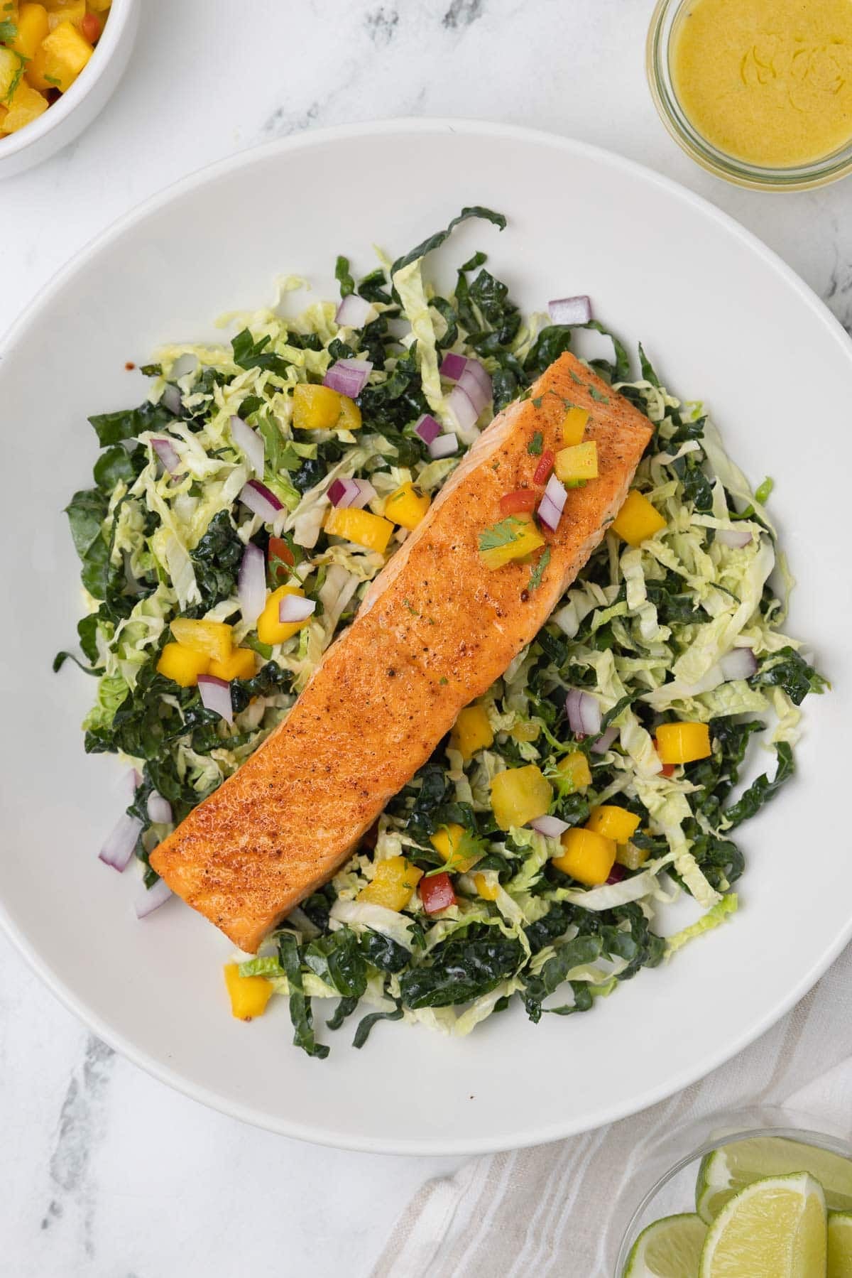 Salmon bowl on a bed of shredded lettuce greens with mango salsa and dijon dressing.
