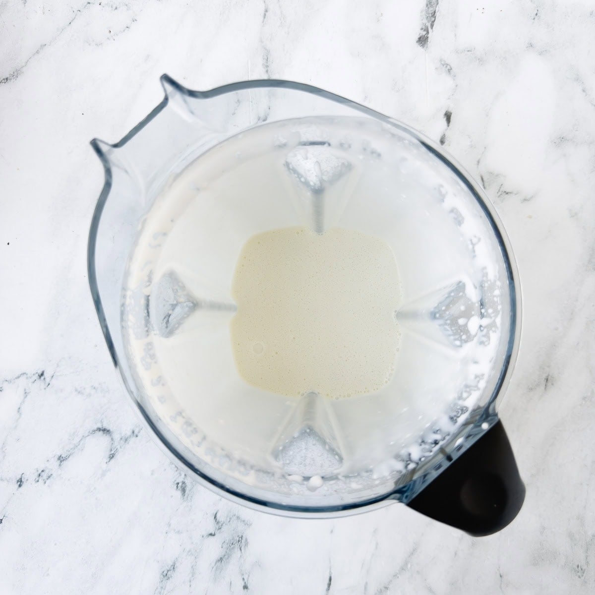 Pureeing cottage cheese and milk in a blender until smooth.